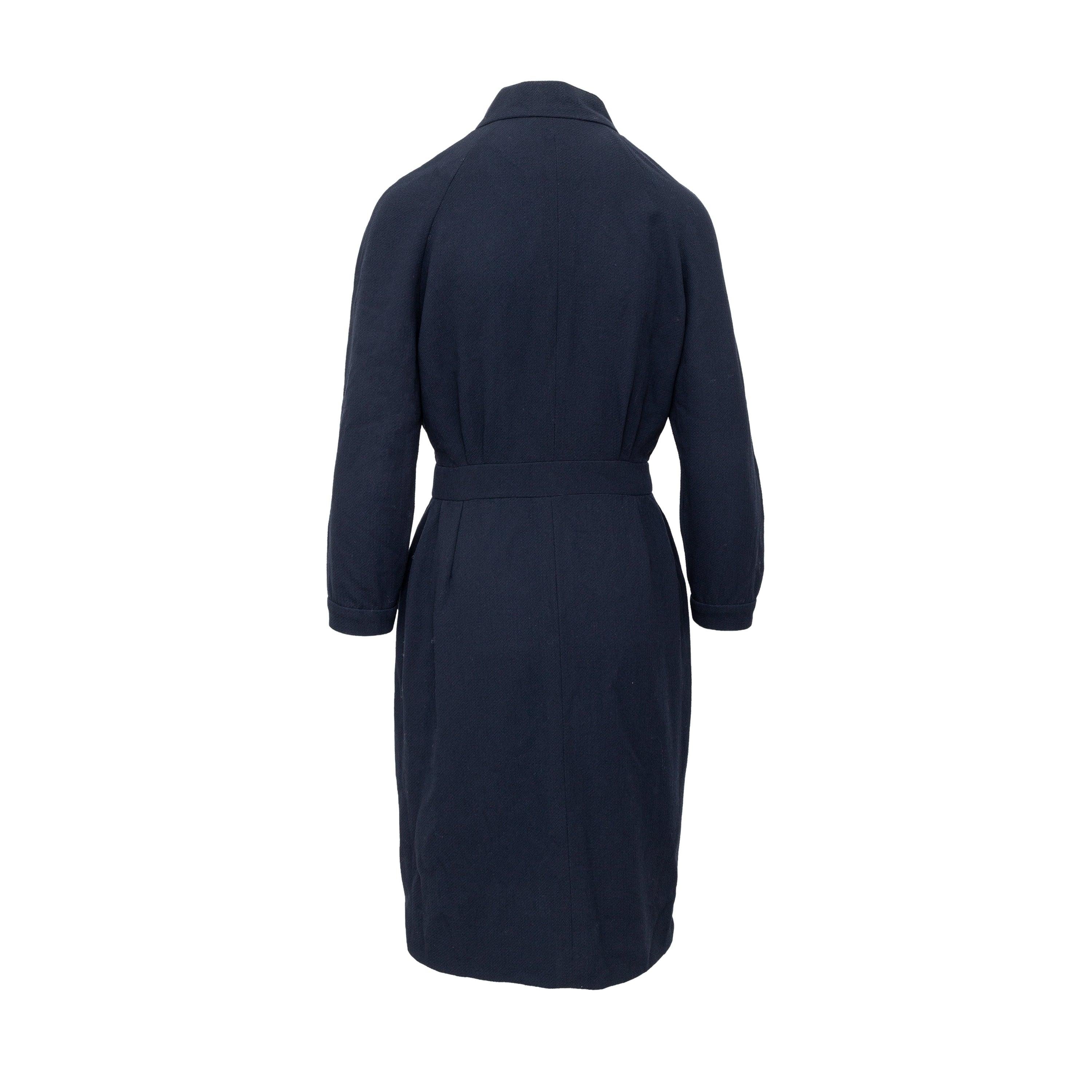 Elevate your wardrobe with the Chanel Boutique Dress. Crafted from a luxurious navy blue crepe fabric, this midi dress features a unique cut high neck and two front pockets for a touch of practicality. Complete with CC logo embossed square buttons,