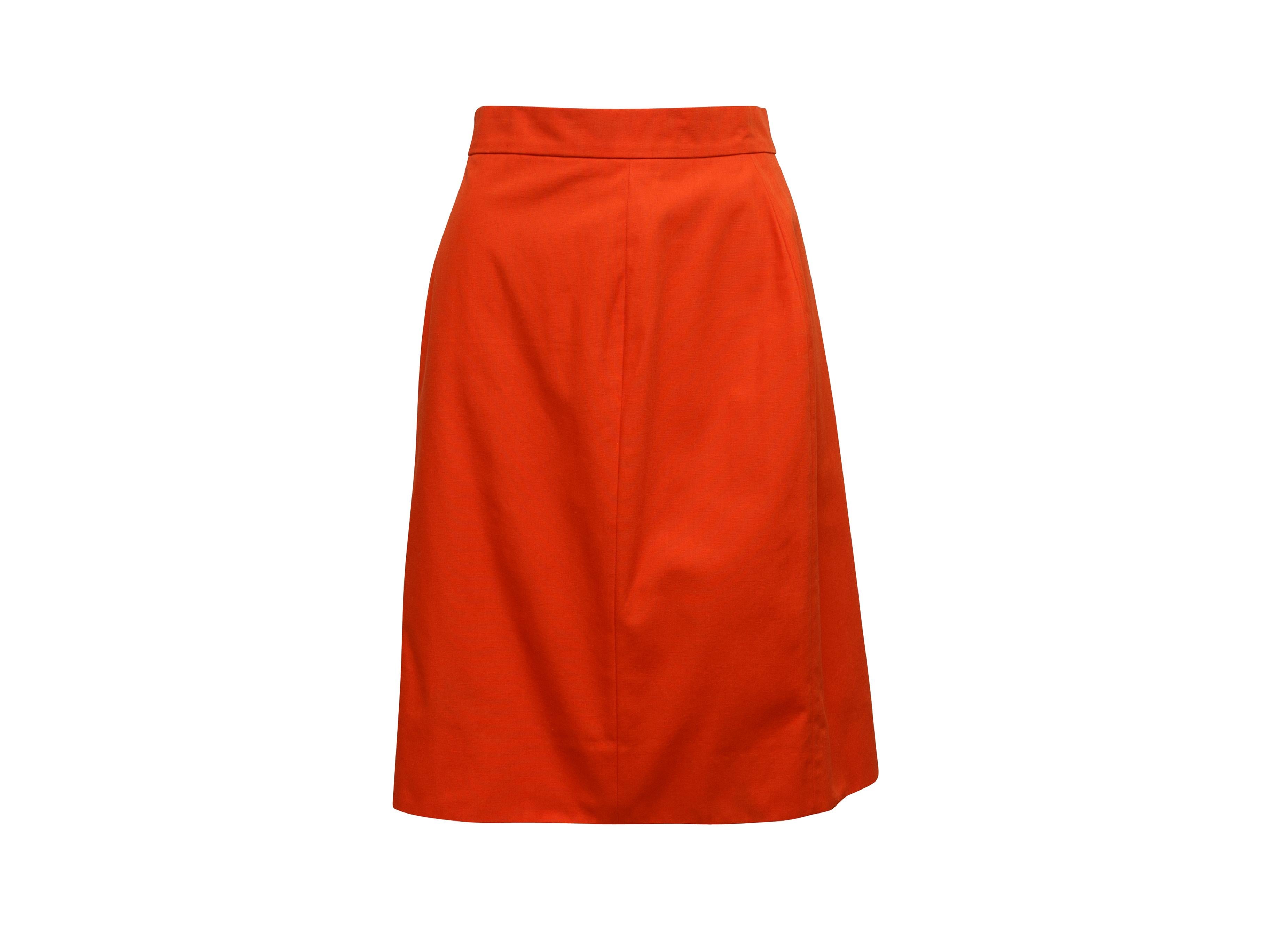 Product details: Vintage bright orange skirt suit by Chanel Boutique. V-neck. Four pockets. Orange and gold-tone CC button closures at front of jacket. Zip closure at skirt. Jacket- 34