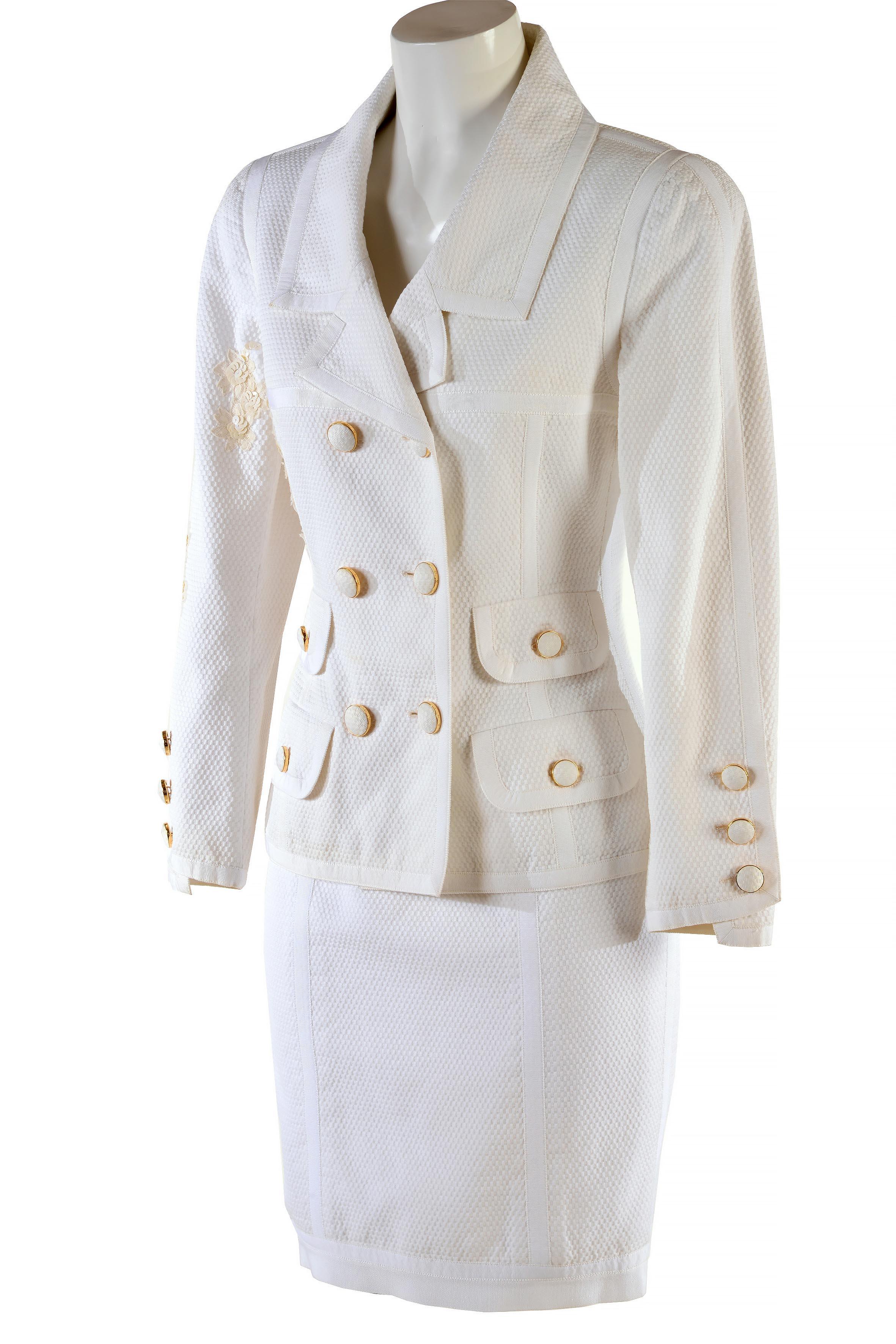 Costume vintage Chanel Boutique de la fin des années 80
Coton piqué blanc 
Veste à double boutonnage dont les boutons sont recouverts du même tissu. Incrustations de paillettes et de fleurs en dentelle.
Doublure en soie
Absence de Label de taille et