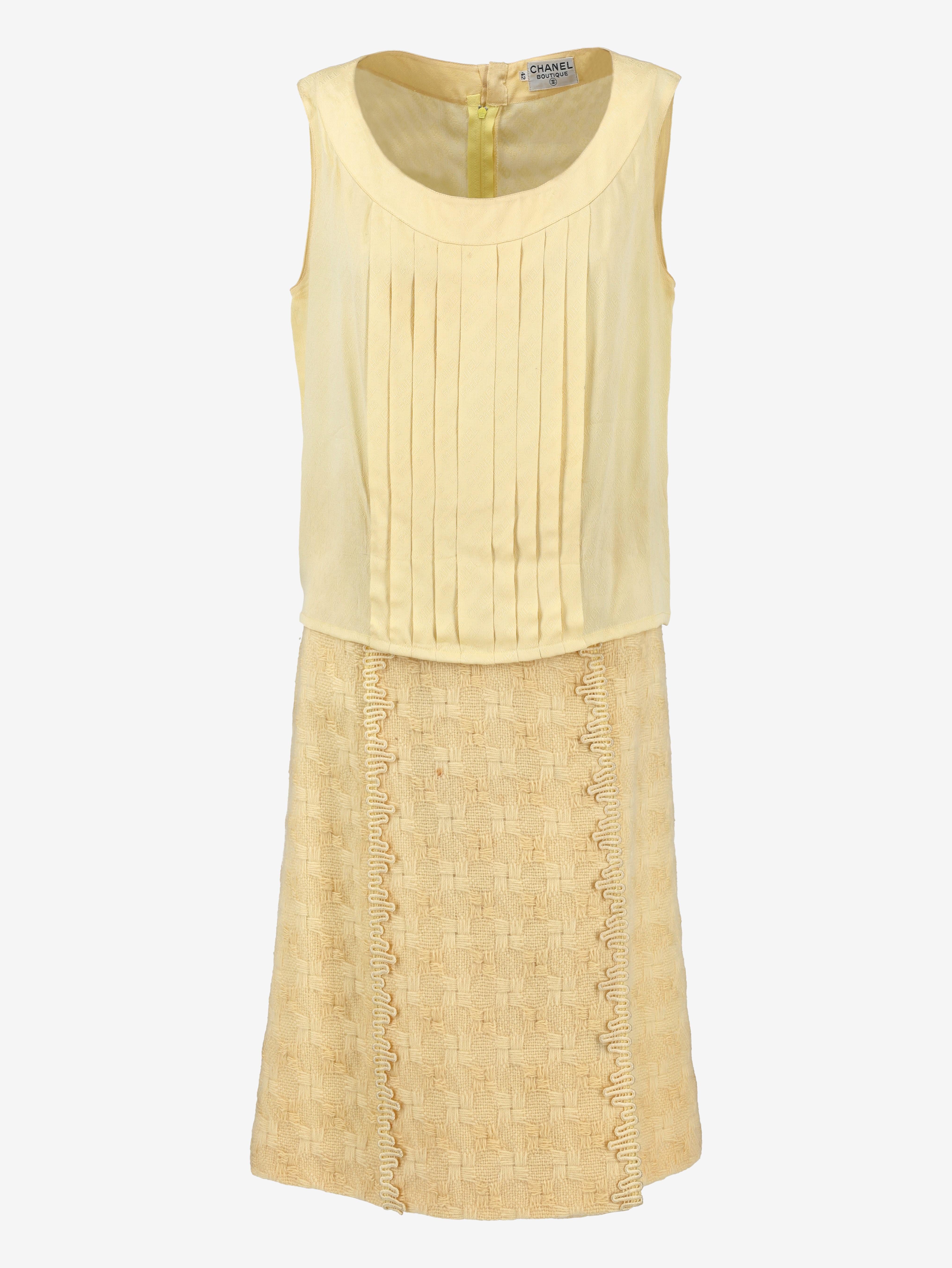 Chanel Boutique Yellow Wool Suit is a three-piece set consisting of a silk top with monogram pattern, round neck and front pleat and a jacket and skirt in heavy wool with criss-cross weave and trimmed trimmings along the edges and pockets. Gold