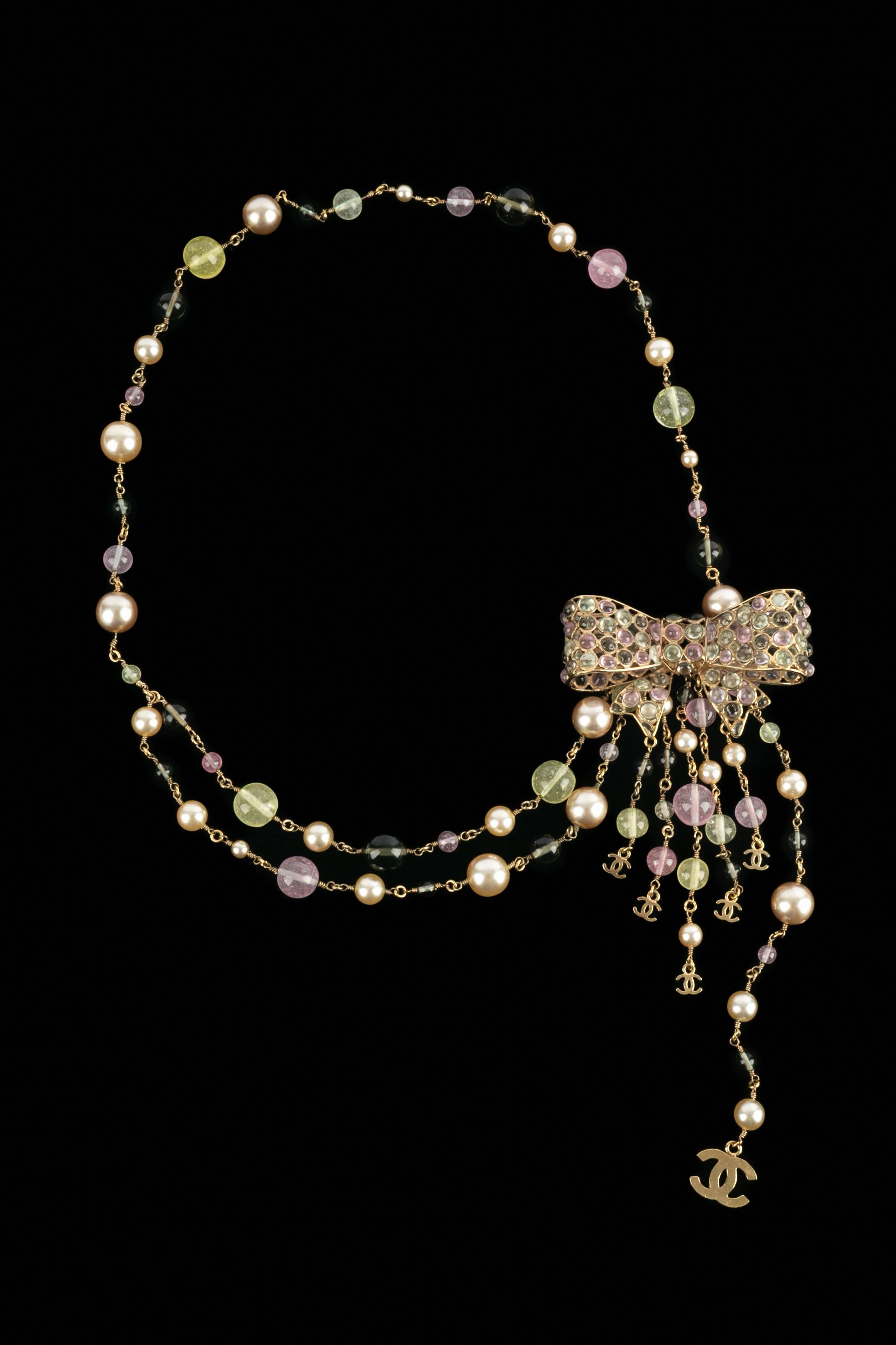 Chanel - (Made in France) Cintura gioiello in metallo dorato con perle di costume e perle di vetro. La fibbia rappresenta un fiocco in pasta di vetro. Collezione Autunno-Inverno 2002 sotto la direzione artistica di Karl