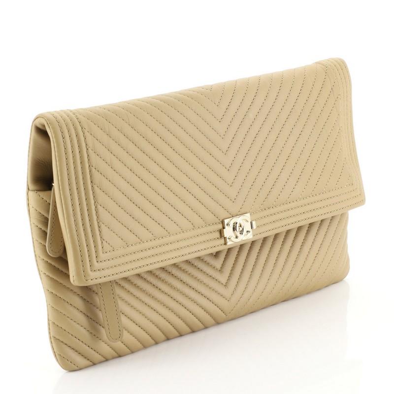 This Chanel Boy Beauty CC Clutch Chevron Leather, crafted from neutral chevron leather, features Boy CC logo and gold-tone hardware. Its zipper flap top opens to a neutral chevron nylon interior. Hologram sticker reads: 21065910. 

Estimated Retail