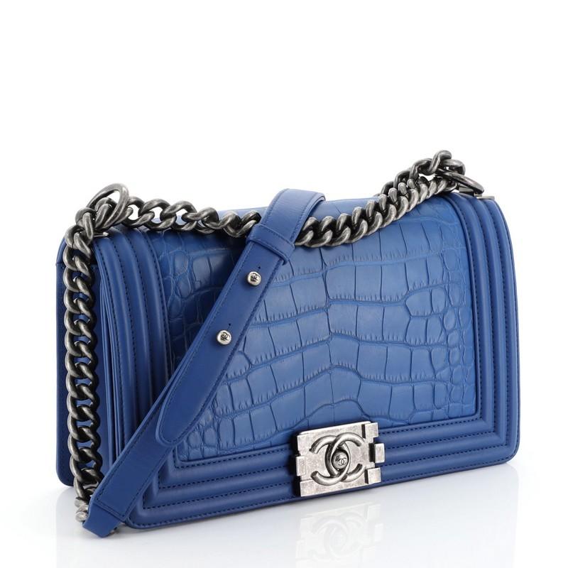 This Chanel Boy Flap Bag Alligator Old Medium, crafted from genuine blue alligator, features chain link strap with shoulder pad and aged silver-tone hardware. Its CC Boy logo push-lock closure opens to a blue leather interior with side slip pocket.
