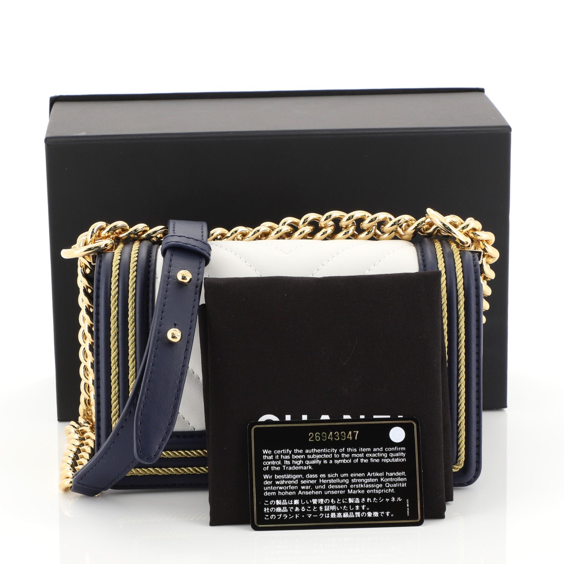 This Chanel Boy Flap Bag Chevron Calfskin with Braided Detail Small, crafted from white and blue chevron calfskin leather, features chain strap with leather shoulder pad, braided detail and gold-tone hardware. Its CC push-lock closure opens to a