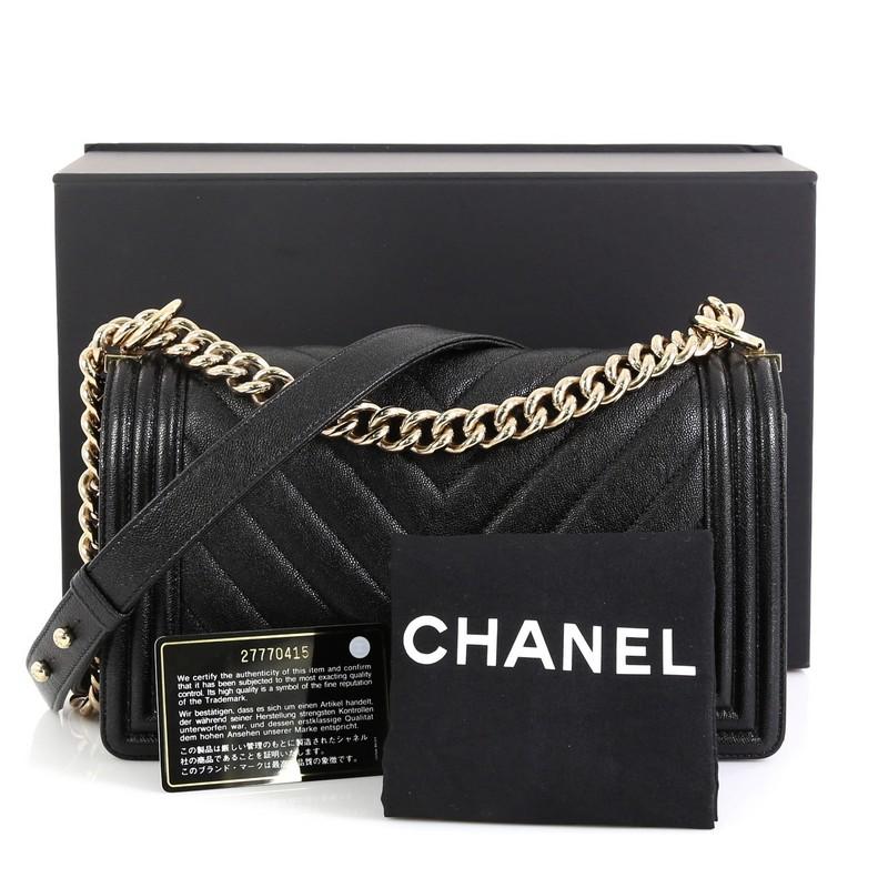 This Chanel Boy Flap Bag Chevron Caviar Old Medium, crafted in black chevron caviar leather, features chain strap with leather shoulder pad and gold-tone hardware. Its Boy push-lock closure opens to a black fabric interior with slip pocket. Hologram