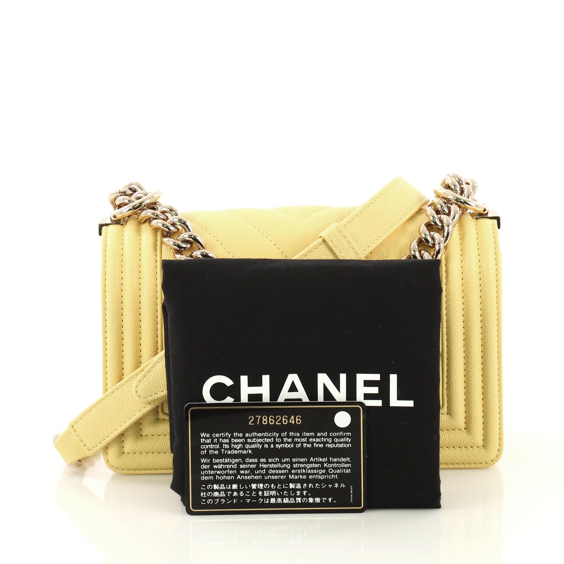 This Chanel Boy Flap Bag Chevron Caviar Small, crafted from yellow chevron caviar leather, features chain link strap with adjustable leather pad and gold-tone hardware. Its CC boy push-lock closure opens to a yellow fabric interior with slip pocket.