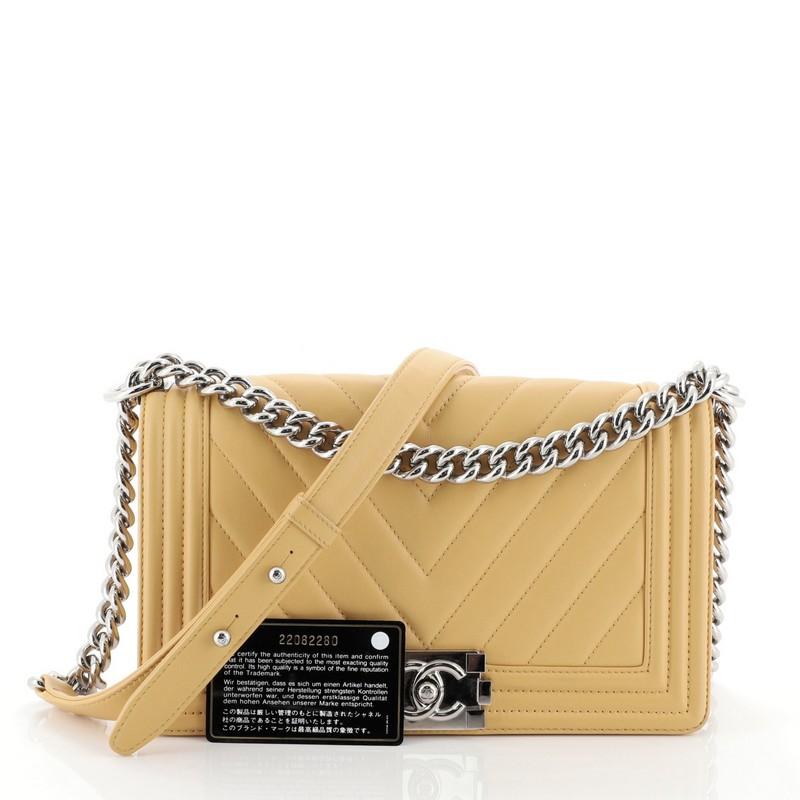 This Chanel Boy Flap Bag Chevron Lambskin Old Medium, crafted in yellow chevron lambskin leather, features chain link strap with leather shoulder pad and silver-tone hardware. Its Boy push-lock closure opens to a gray fabric interior with slip
