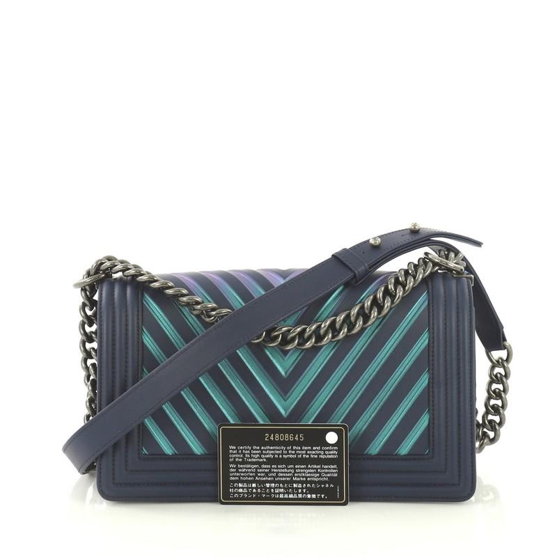 This Chanel Boy Flap Bag Chevron Painted Calfskin Old Medium, crafted from blue chevron painted calfskin leather, features chain link strap with leather pad and aged silver-tone hardware. Its CC Boy push lock closure opens to a blue fabric interior