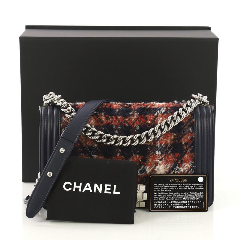 This Chanel Boy Flap Bag Chevron Tweed Old Medium, crafted in navy and red chevron tweed, features chain link strap with leather pad and silver-tone hardware. Its Boy push-lock closure opens to a red fabric interior with slip pocket. Hologram