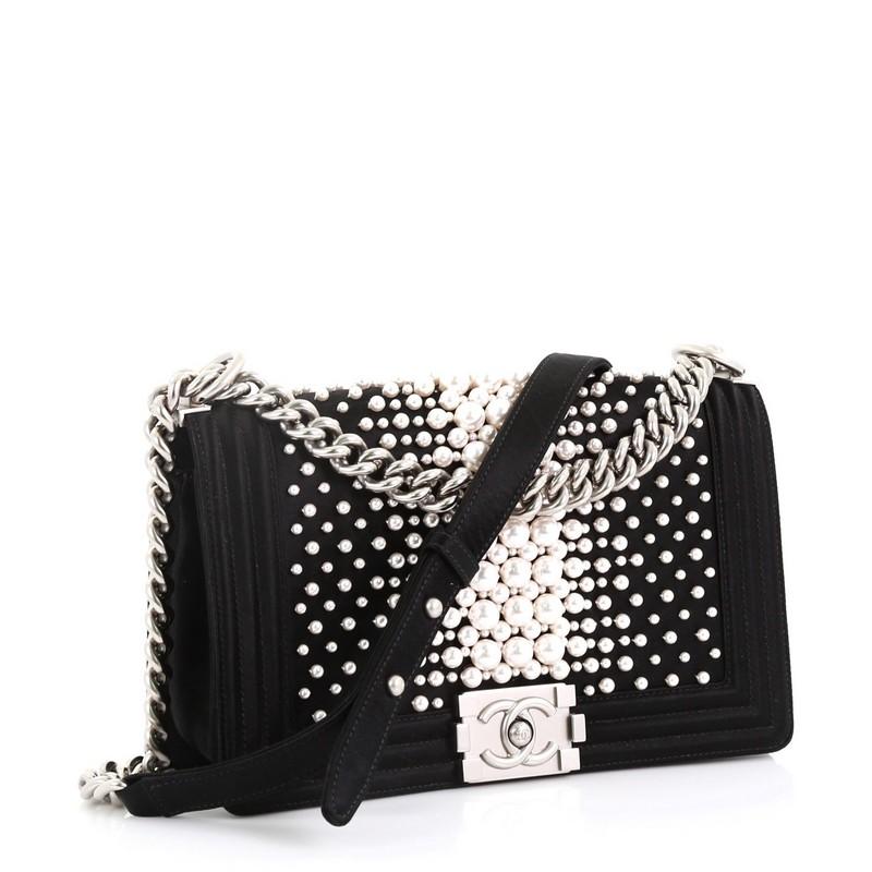 This Chanel Boy Flap Bag Pearl Embellished Satin Old Medium, crafted in pearl embellished black satin, features chain link strap with leather pad and matte silver-tone hardware. Its boy push-lock closure opens to a black satin interior with side
