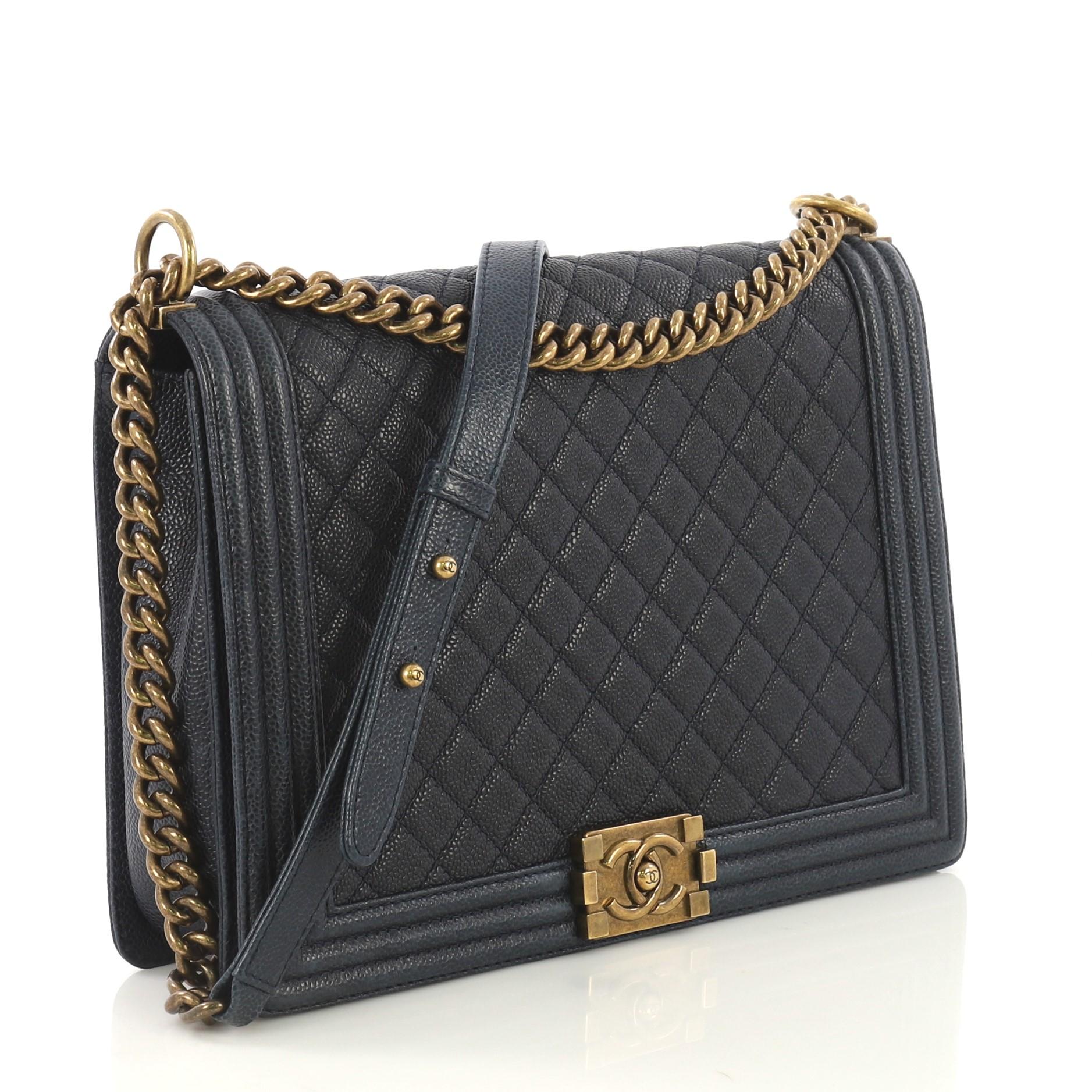 This Chanel Boy Flap Bag Quilted Caviar Large, crafted from navy quilted caviar leather, features chain link strap with leather shoulder pad and aged gold-tone hardware. Its CC boy logo push-lock closure opens to a navy fabric interior with zip and