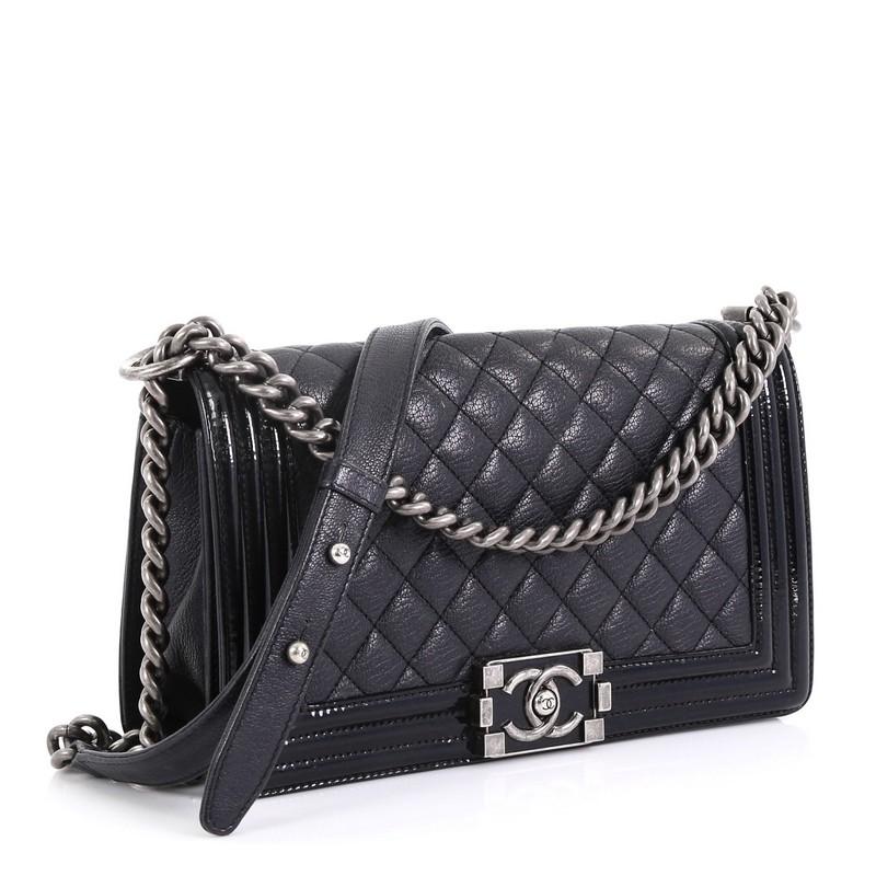 This Chanel Boy Flap Bag Quilted Goatskin with Patent Old Medium, crafted from blue quilted goatskin with patent leather, features chain link strap with leather shoulder pad and aged silver-tone hardware. Its CC boy push-lock closure opens to a