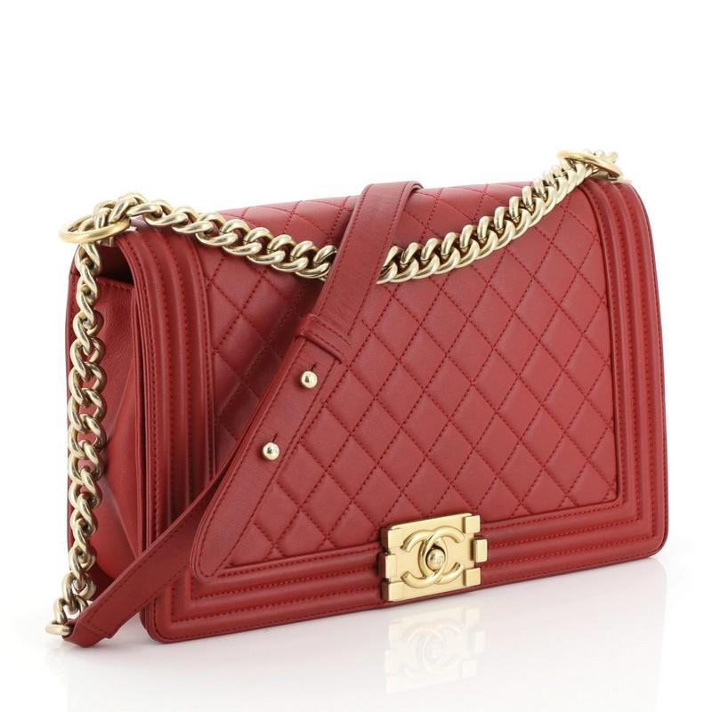 This Chanel Boy Flap Bag Quilted Lambskin New Medium, crafted from red quilted lambskin leather, features chain link strap with leather shoulder pad and gold-tone hardware. Its CC boy logo push-lock closure opens to a red fabric interior with zip