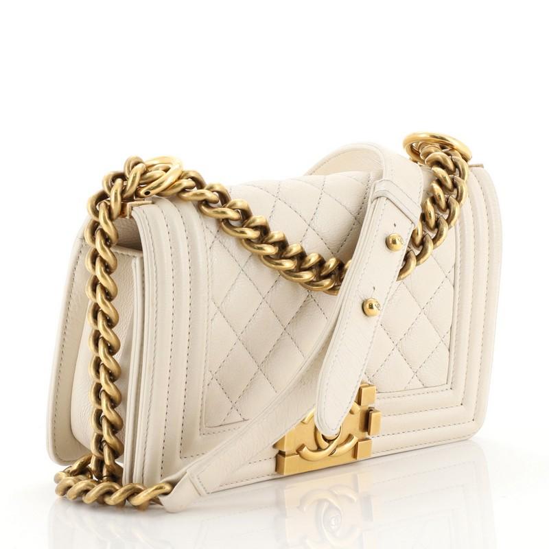 This Chanel Boy Flap Bag Quilted Lambskin Small, crafted from neutral quilted lambskin leather, features chain link strap with leather shoulder pad and aged gold-tone hardware. Its CC boy logo push-lock closure opens to an orange fabric interior