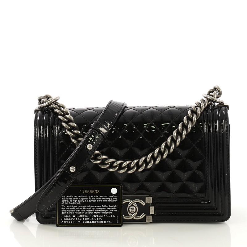 This Chanel Boy Flap Bag Quilted Patent Old Medium, crafted in black quilted patent, features chain link strap with leather pad and aged silver-tone hardware. Its Boy push-lock closure opens to a black fabric interior with slip pocket. Hologram