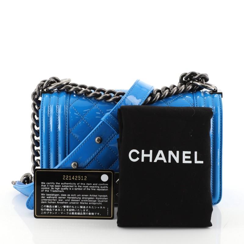 This Chanel Boy Flap Bag Quilted Patent Small, crafted in blue quilted patent leather, features a chain link strap with leather pad and aged silver-tone hardware. Its Boy push-lock closure opens to a blue fabric interior with slip pocket. Hologram