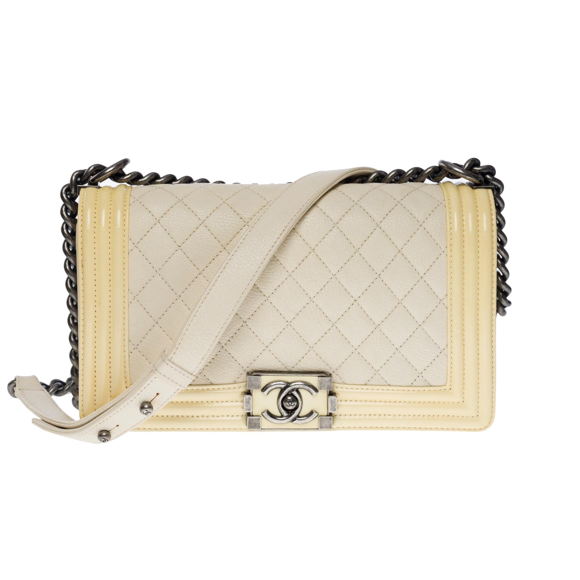 The Iconic Chanel Boy Old Medium shoulder bag in beige caviar leather with yellow varnish outline/frame, ruthenium silver metal hardware, an adjustable ruthenium metal chain handle for shoulder or crossbody carry

A ruthenium metal closure on