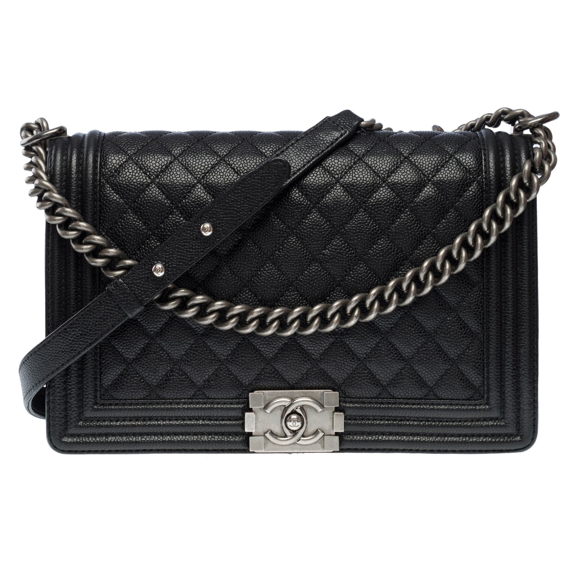 Chanel​ ​Boy​ ​New​ ​Medium​ ​28​ ​cm​ ​shoulder​ ​bag​ ​in​ ​black​ ​quilted​ ​caviar​ ​leather,​ ​ruthenium​ ​metal​ ​trim,​ ​an​ ​adjustable​ ​chain​ ​handle​ ​in​ ​silver​ ​metal​ ​allowing​ ​a​ ​shoulder​ ​or​ ​crossbody​ ​carry

A​ ​ruthenium​