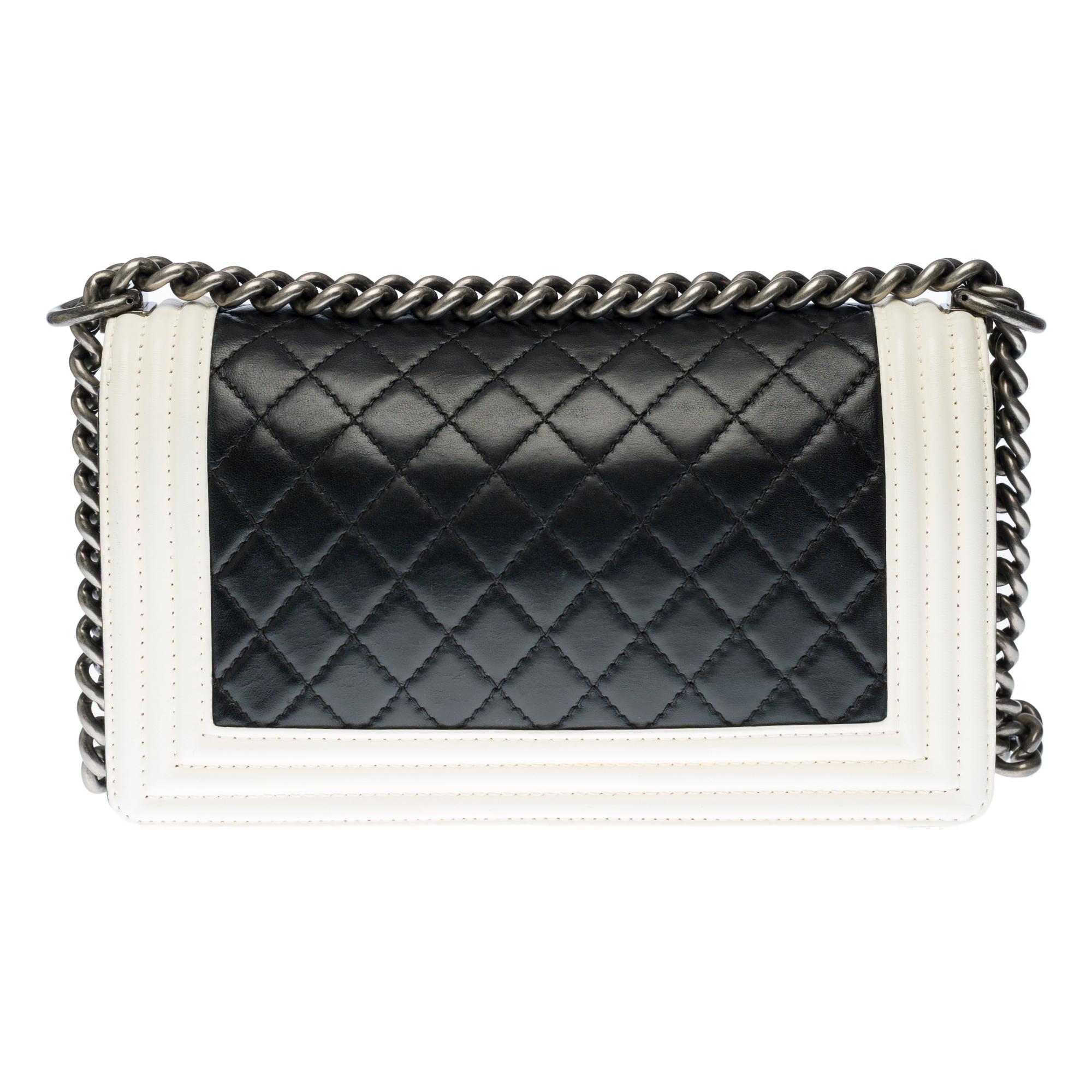 The iconic Chanel Boy shoulder bag in black quilted leather with white leather contour, upholstered in aged silver metal (shotgun barrel), an adjustable chain handle in silver metal allowing a shoulder or shoulder strap.

An antique silver metal