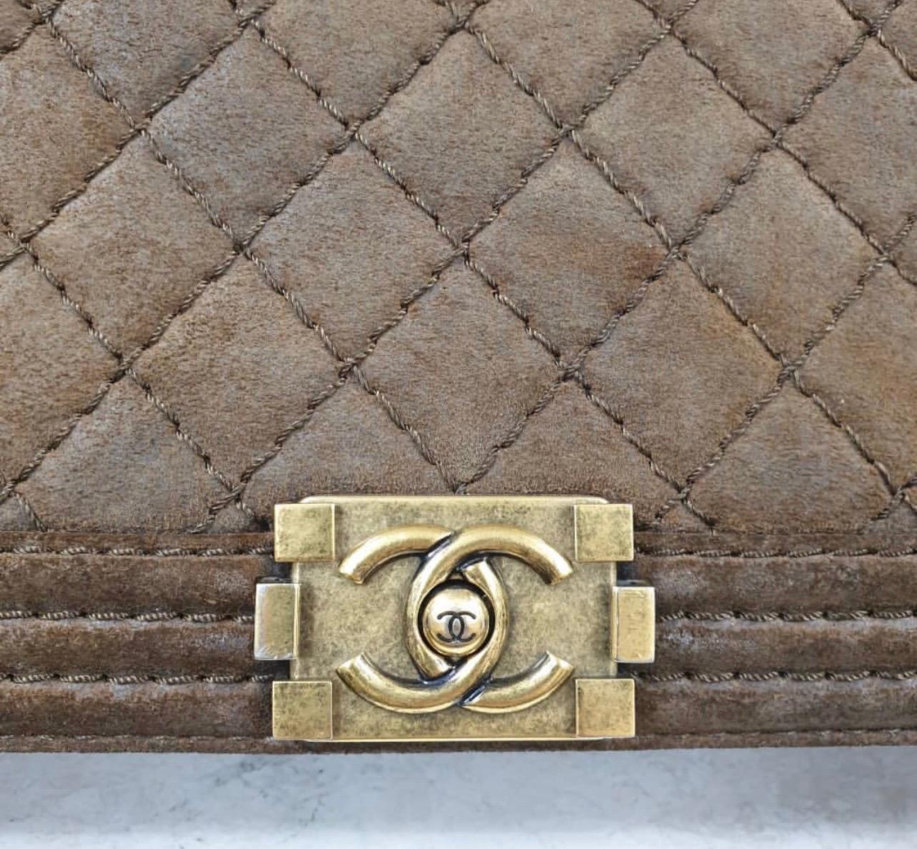 This authentic Chanel Boy Flap Bag Quilted Distressed Suede Large presented in the brand's Pre-Fall 2013 Metiers d'Art Paris Edinburgh Collection is every woman's dream. 
Crafted from khaki brown quilted distressed suede, this popular, enviable Boy