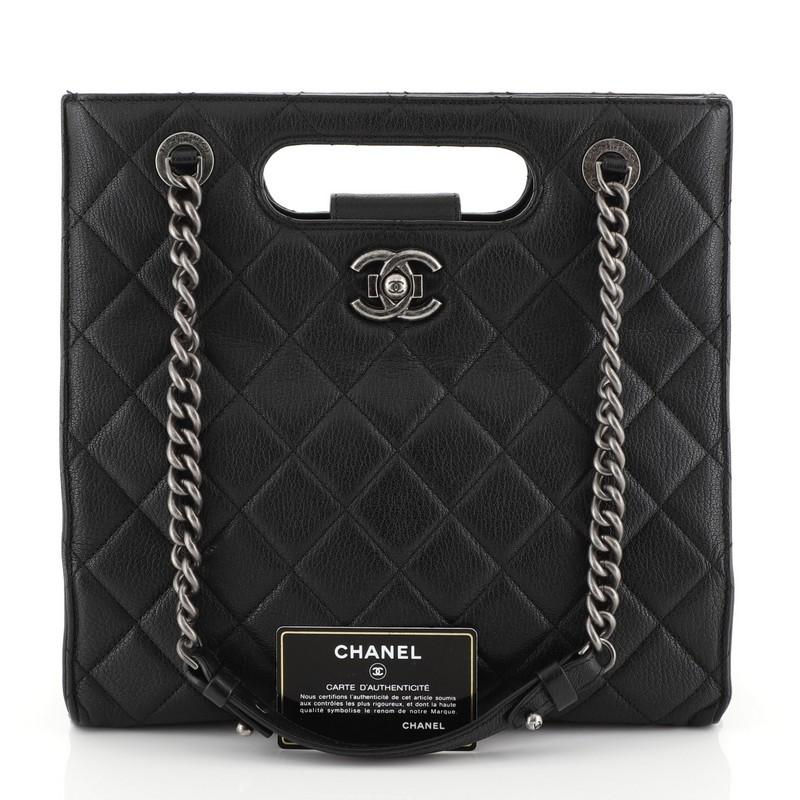 This Chanel Boy Shopper Quilted Goatskin Small, crafted from black quilted goatskin leather, features dual chain link straps with leather pads, cut-out handles, protective base studs, and aged silver-tone hardware. Its CC Boy push-lock closure opens