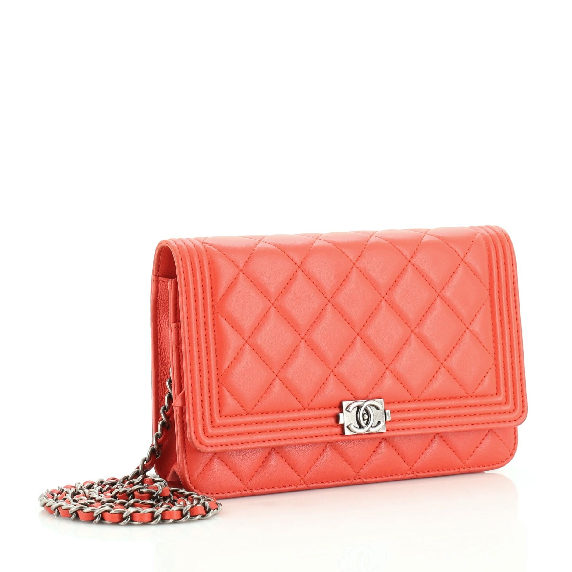 This Chanel Boy Wallet on Chain Quilted Lambskin, crafted from red quilted lambskin leather, features woven-in leather chain strap, Chanel boy insignia, and aged silver-tone hardware. Its snap button closure opens to a red fabric interior with side