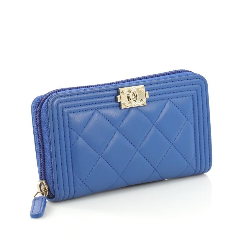 This Chanel Boy Zip Around Wallet Quilted Lambskin Long, crafted from blue quilted lambskin, features the faux CC boy push-lock and gold-tone hardware. Its all-around zip closure opens to a blue leather interior divided into two gusseted