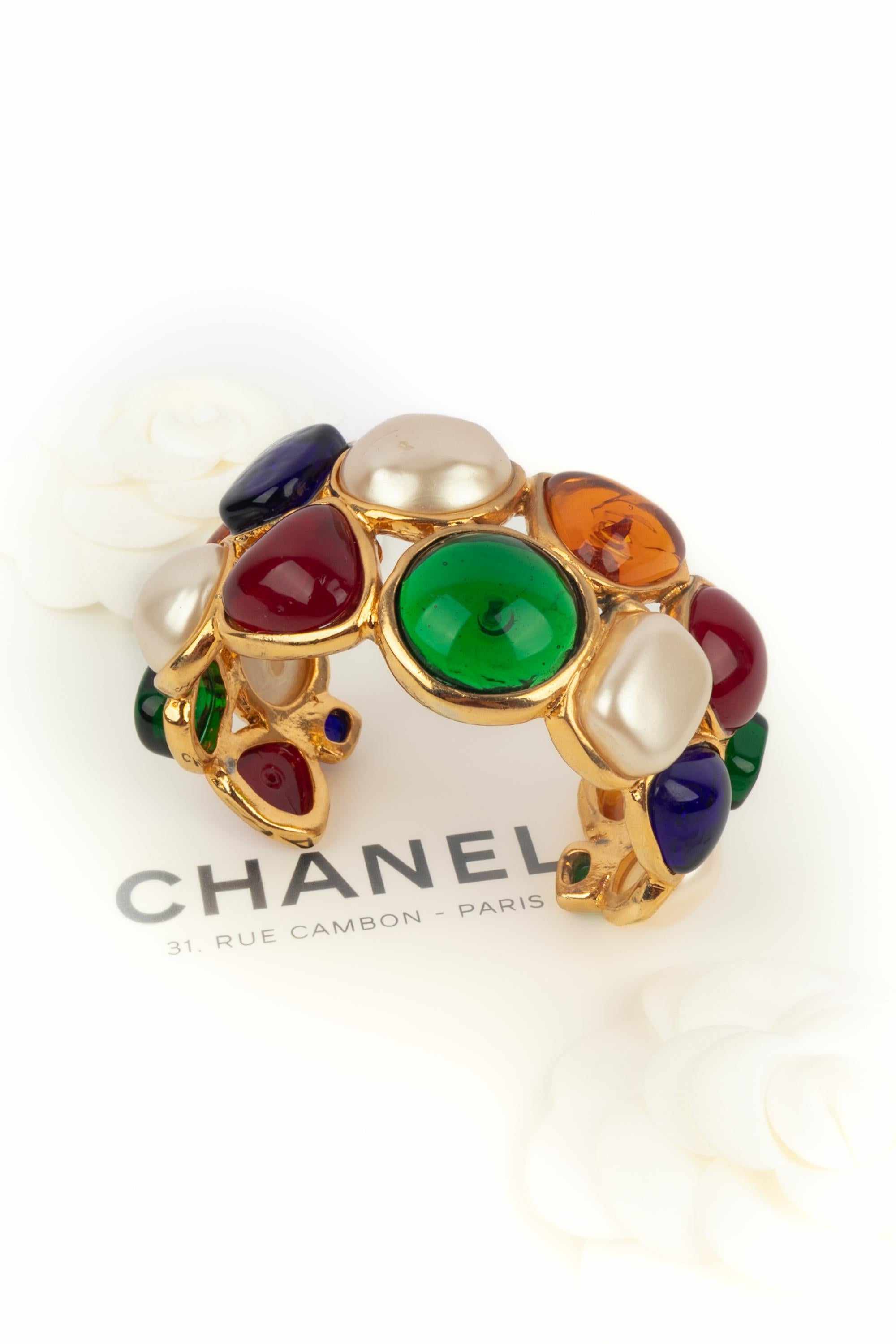 CHANEL - (Fabriqué en France) Bracelet manchette en métal doré, cabochons nacrés avec pâte de verre. Une Collection S sous la direction artistique de Karl Lagerfeld.

Condit :
Très bon état.

Dimensions :
Circonférence : 15 cm - Ouverture : 3,5 cm -