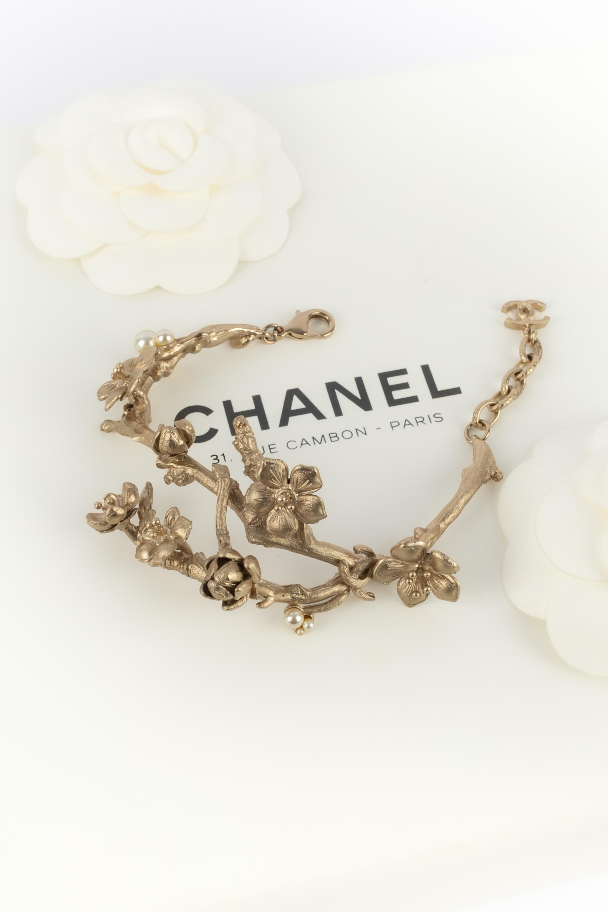 CHANEL - (Made in France) Pulsera articulada de metal color champán que representa ramas y flores. Colección de 2014 bajo la dirección artística de Karl Lagerfeld.

Estado:
Muy buen estado

Dimensiones:
Longitud: de 17 cm a 21 cm

SKU:BRAB123