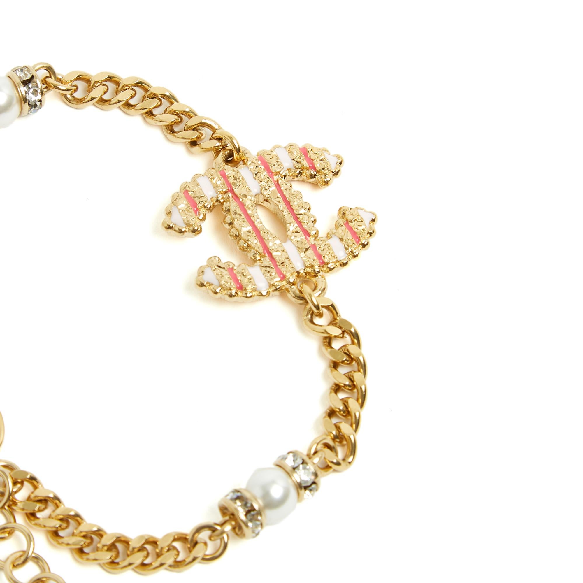 Chanel bracelet in gold-plated metal composed of a curb chain interspersed with rhinestones and fancy pearls and a large CC logo enameled with pale pink and strong pink stripes, clasp closure (engraved) on a chain ending with a small CC logo, year