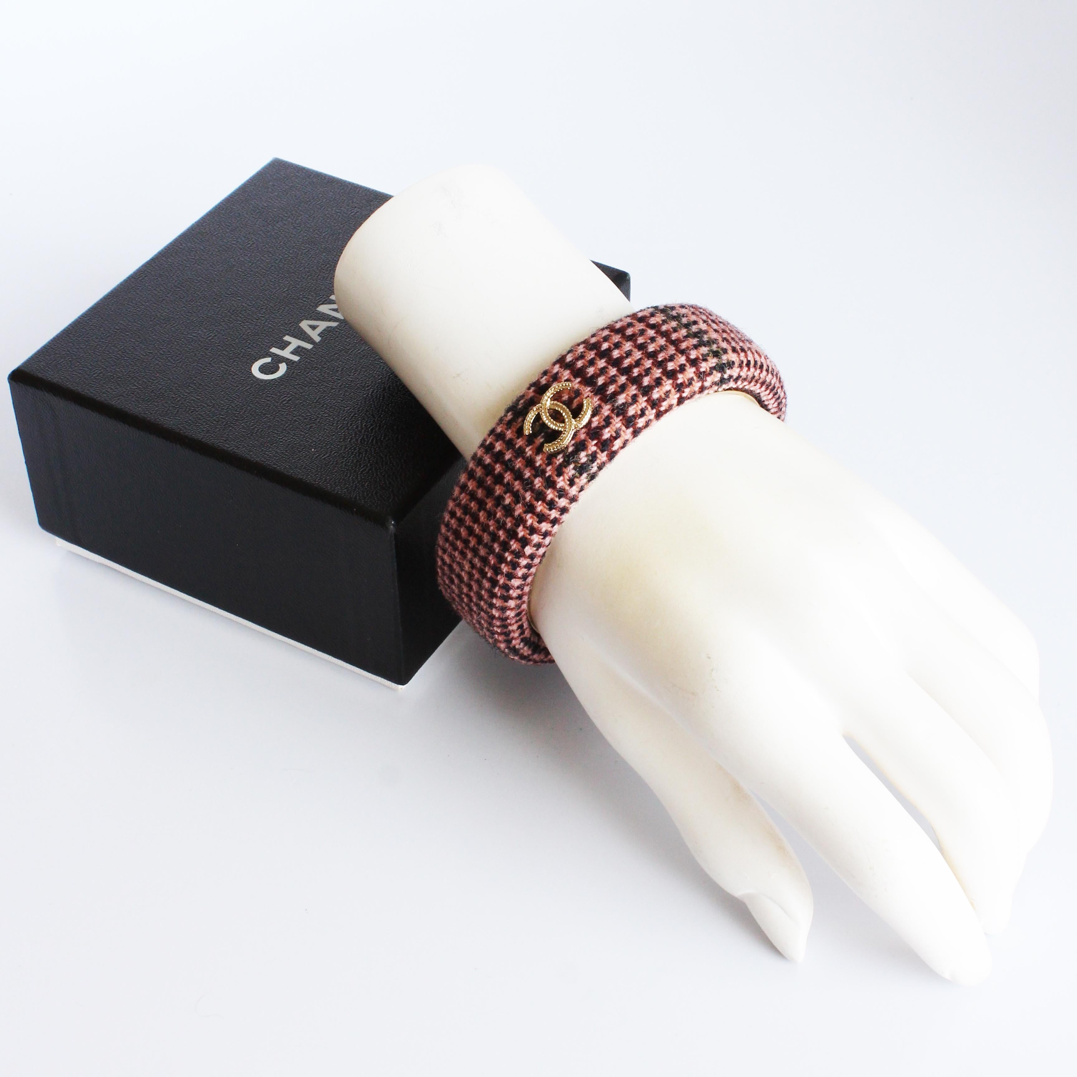 Preowned Chanel pink tweed bangle bracelet from the 13A collection.  Made from a pink multi color tweed fabric, if features Chanel's interlocking CC's in textured gold metal, and a gold metal base.

Fabulous and sophisticated, the tweed fabric and