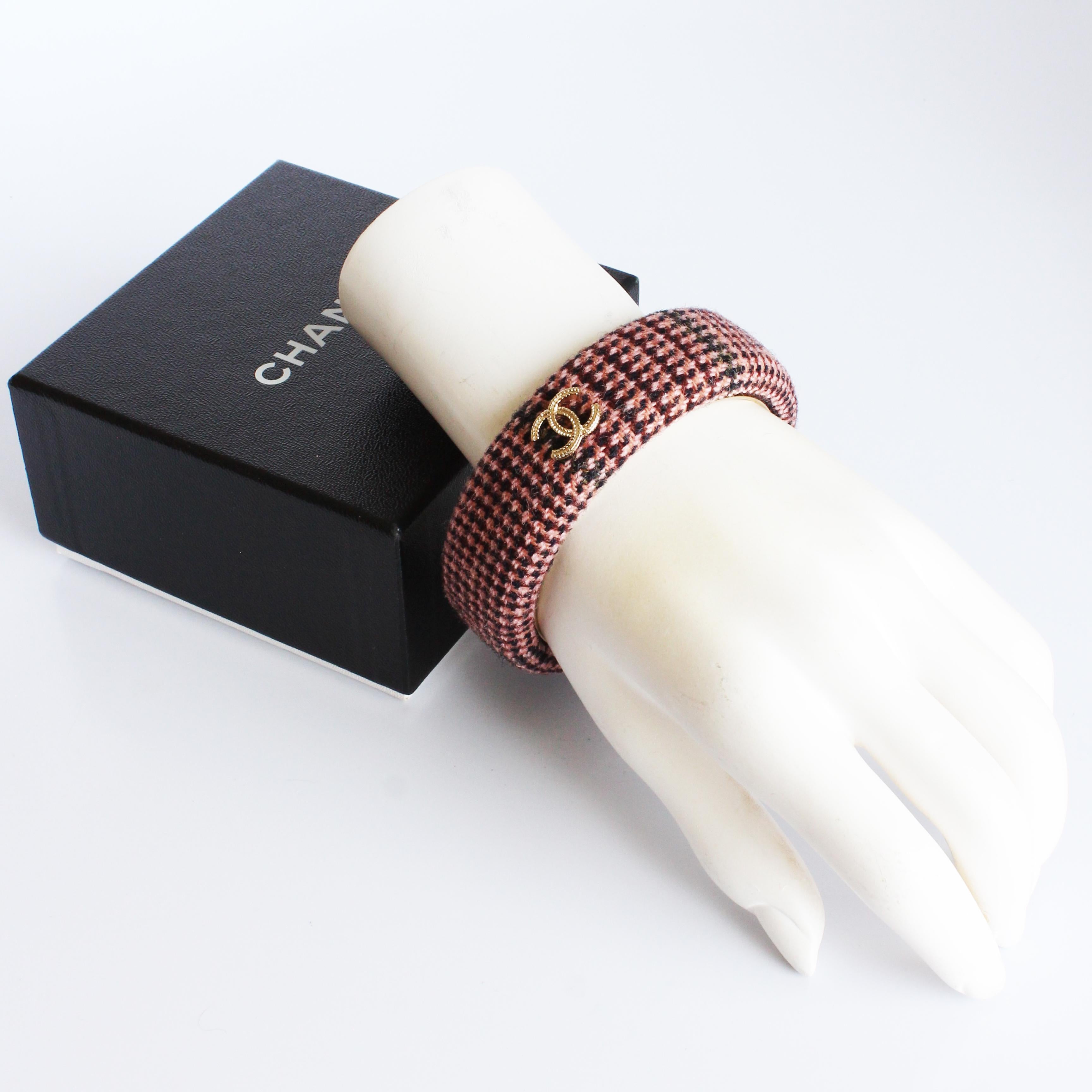 Bracciale bangle in tweed rosa Chanel usato della collezione 13A.  Fabrice in tessuto tweed rosa multicolore, presenta le CC intrecciate di Chanel in metallo dorato e una base in metallo dorato.

Fabrice e sofisticata, il tessuto tweed e le CC in