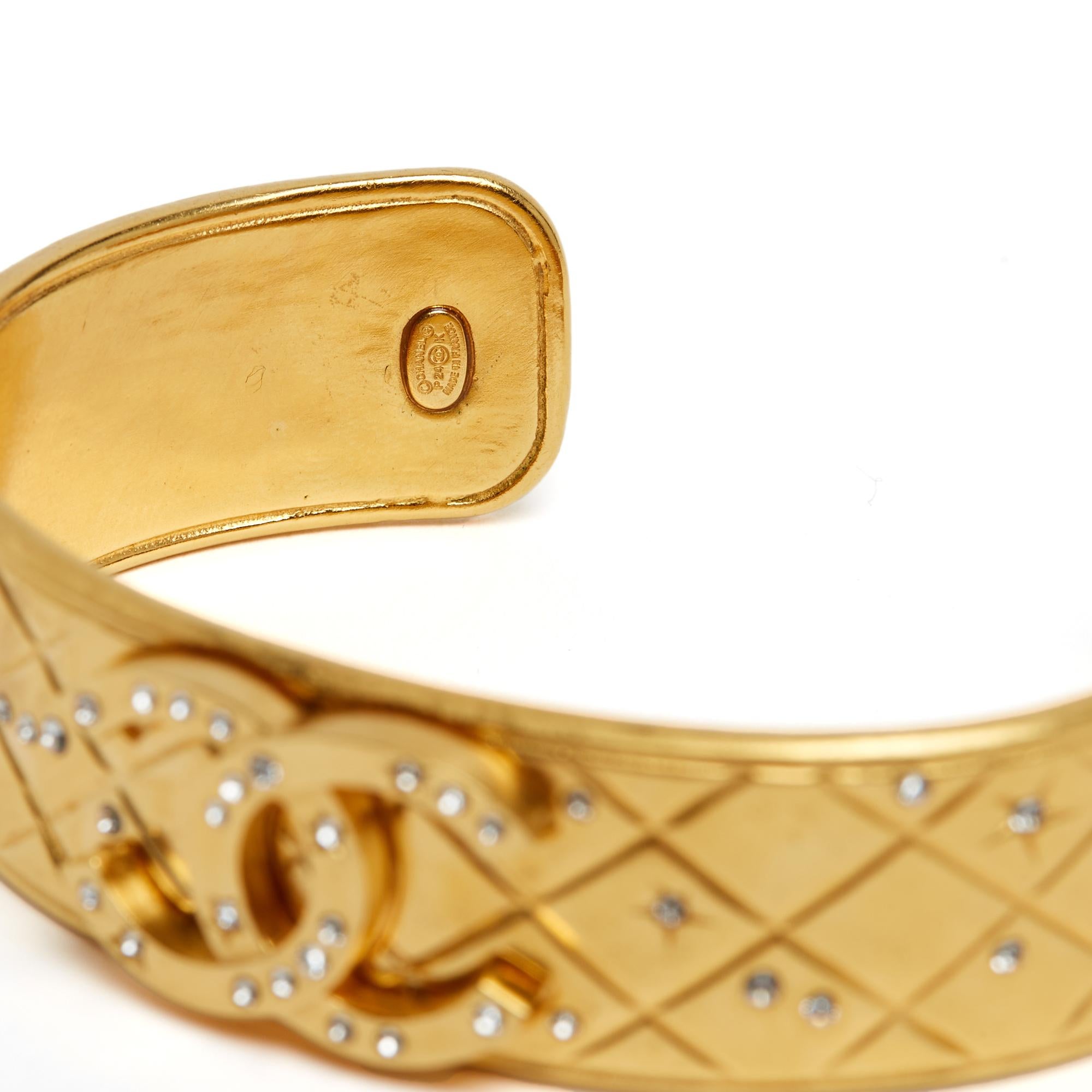 Brazalete Chanel, colección Resort o PE 2024, abierto en metal dorado acolchado rematado con un gran logotipo CC, todo incrustado con microestrás blanco. Ancho de la pulsera 1,65 cm. El tamaño de la pulsera es 