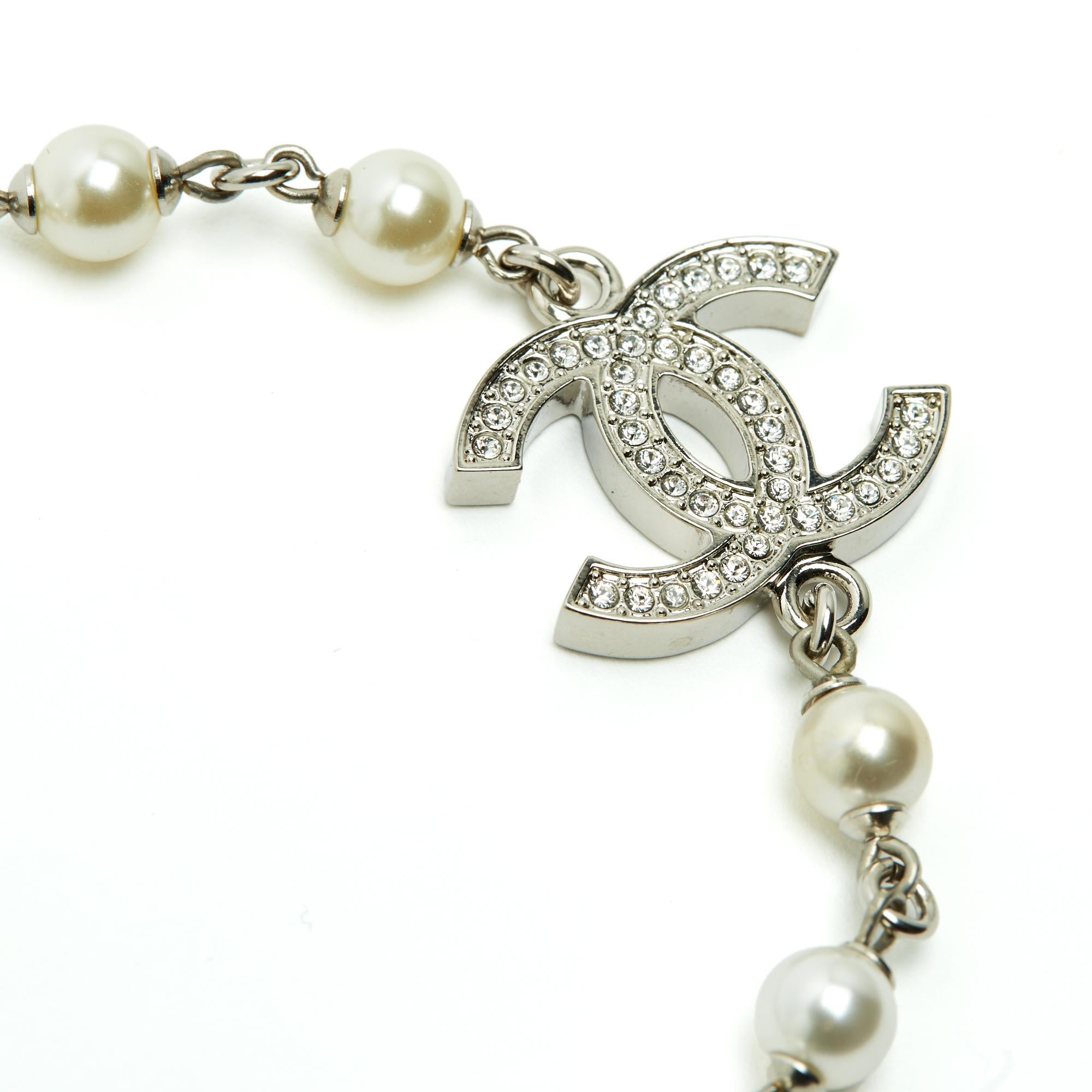 Bracelet Chanel 2023 en métal argenté, présentant des perles fantaisie entrecoupées d'un grand logo CC plat incrusté de minuscules strass blancs. Il se ferme à l'aide d'un fermoir en forme de homard signé sur une chaîne terminée par un petit logo