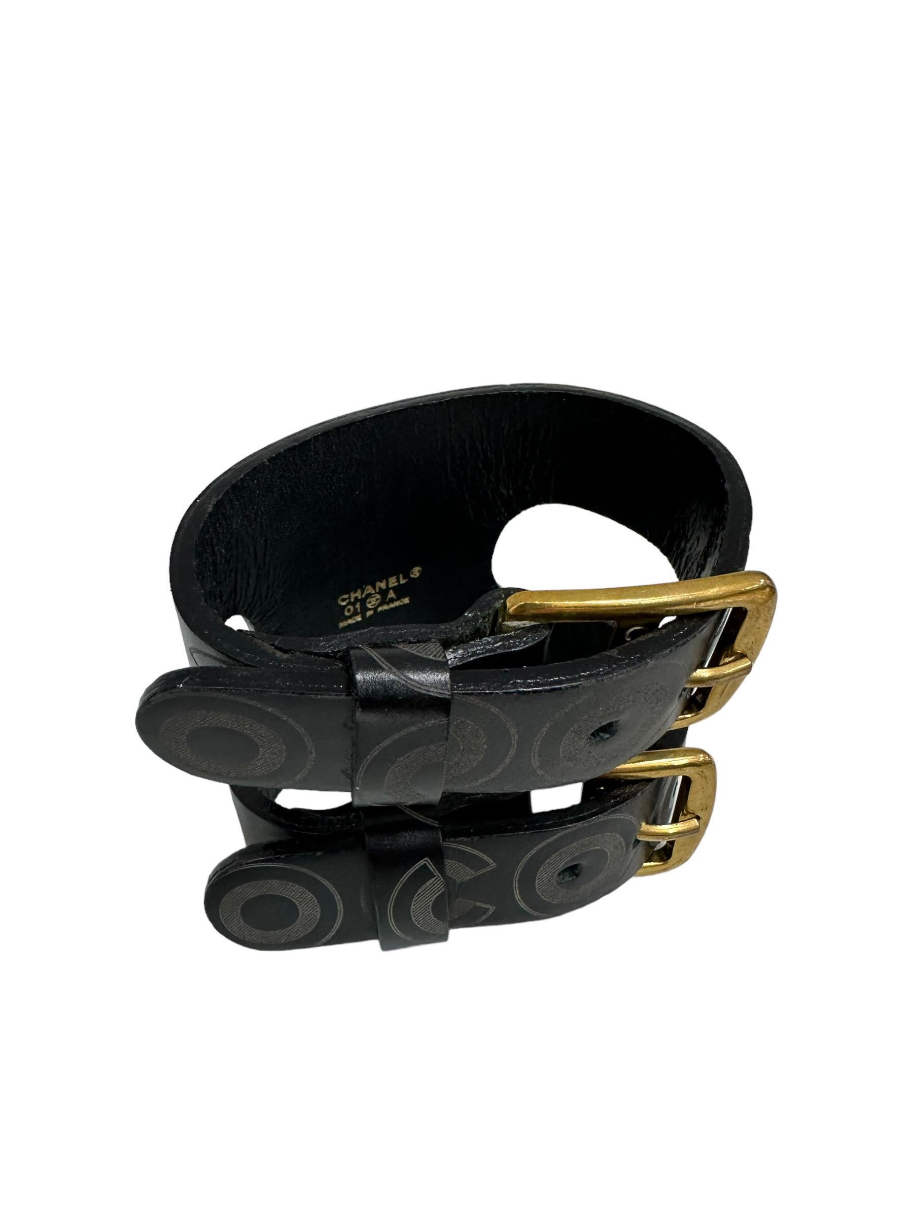 Chanel signed bracelet, Coco Print model, made in black leather with gold hardware. Equipped with an opening with two adjustable buckles. One size. It is presented in good condition.