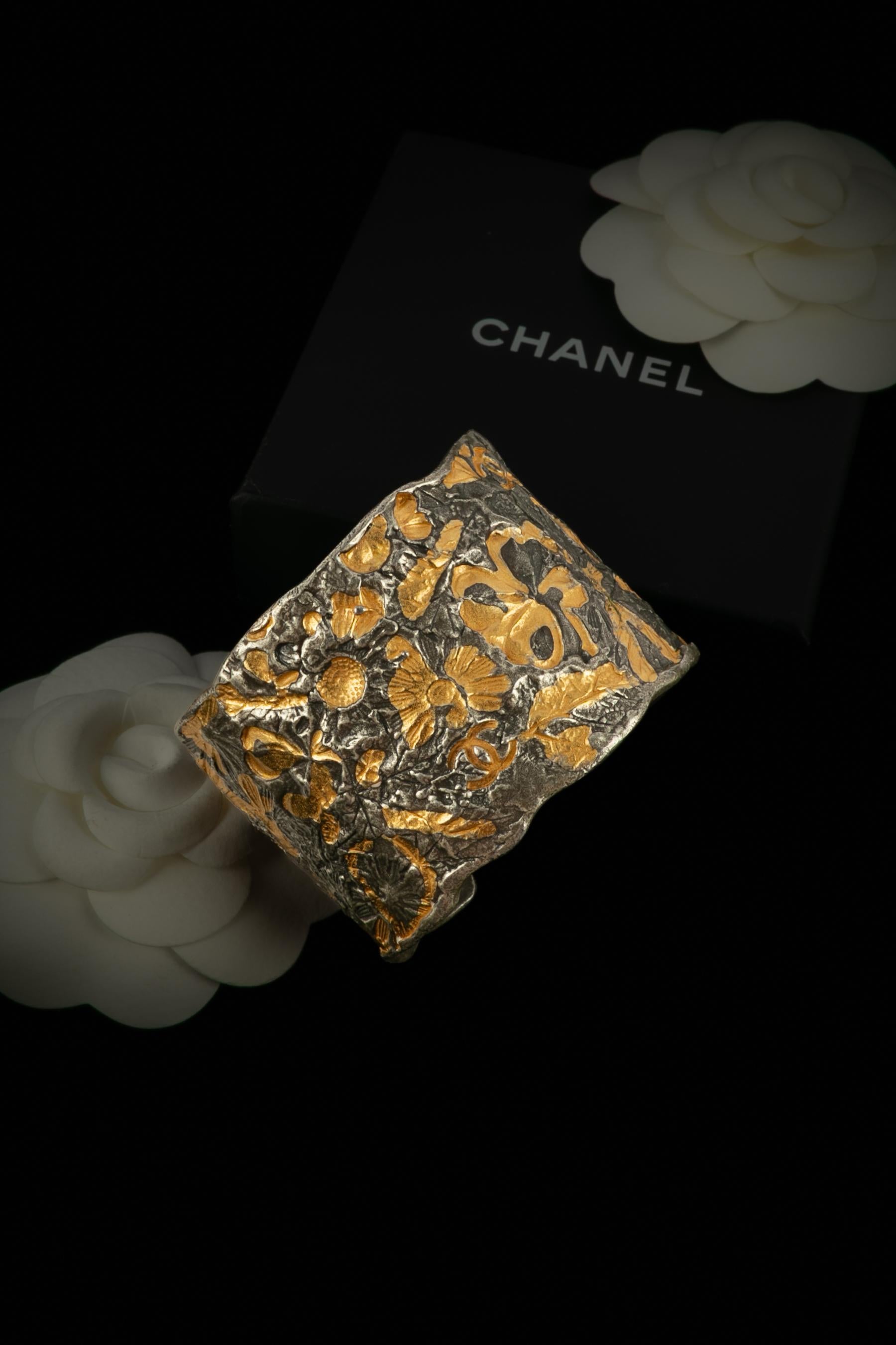 CHANEL - (Made in France) Graviertes silbernes und goldenes Metallarmband. Cruise Collection'S 1998 unter der künstlerischen Leitung von Karl Lagerfeld.

Bedingung:
Sehr guter Zustand

Abmessungen:
Länge: 13,5 cm - Öffnung: 3 cm

SKU:BRAB15