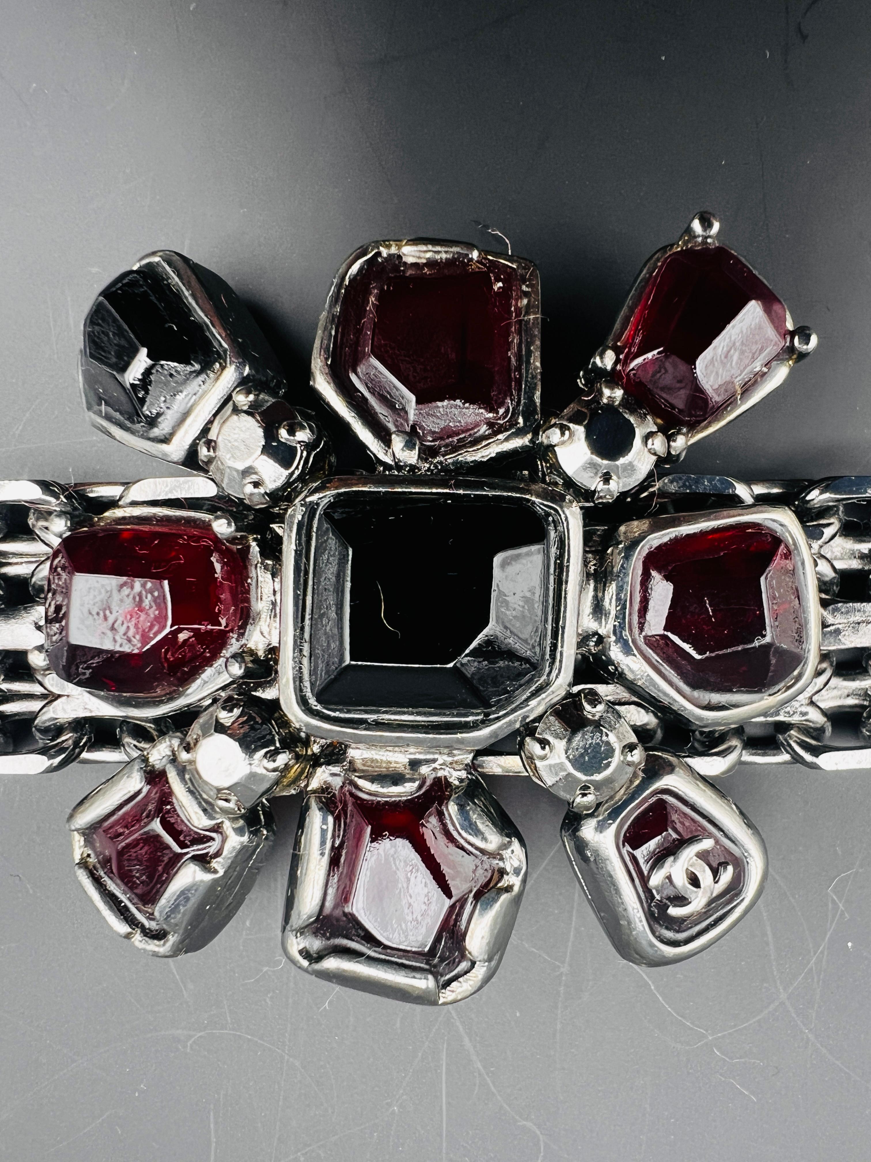 Bracelet Chanel avec ornement Gripoix en verre fondu rouge foncé et noir au centre.  Chaîne en acier Chanel . Logo Chanel sur une pierre.
Estampille Chanel au dos 2002
Fabriqué en France.
 