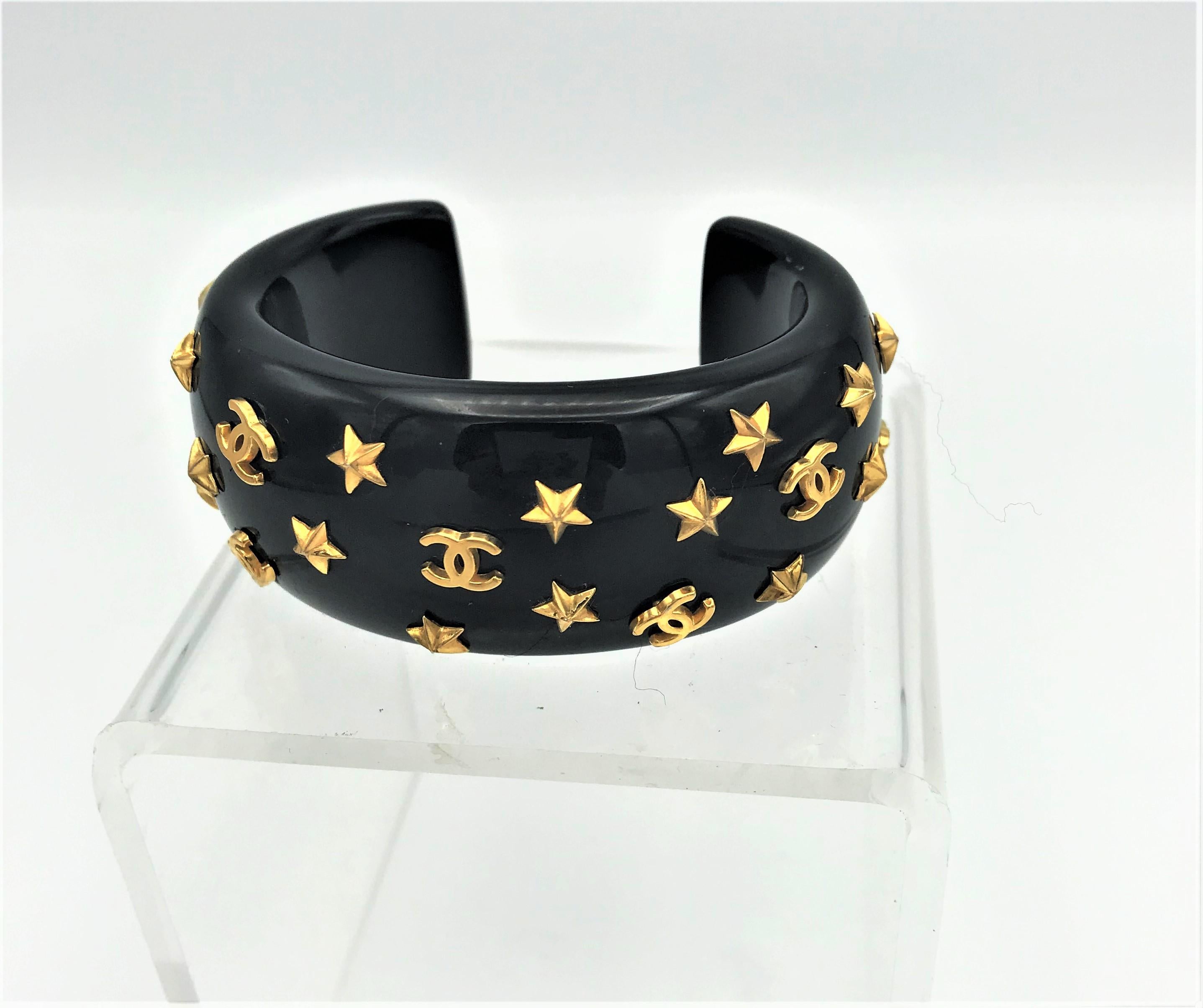 Lovely black bracelet - cuff ore manschet constellated molded plastic from the autum-winter collection 1995. Busy with many gold  stars and 10 unique Chanel CCs,  designed by  Victoire de Castellane. signed on a plate inside.
Measurement: The height
