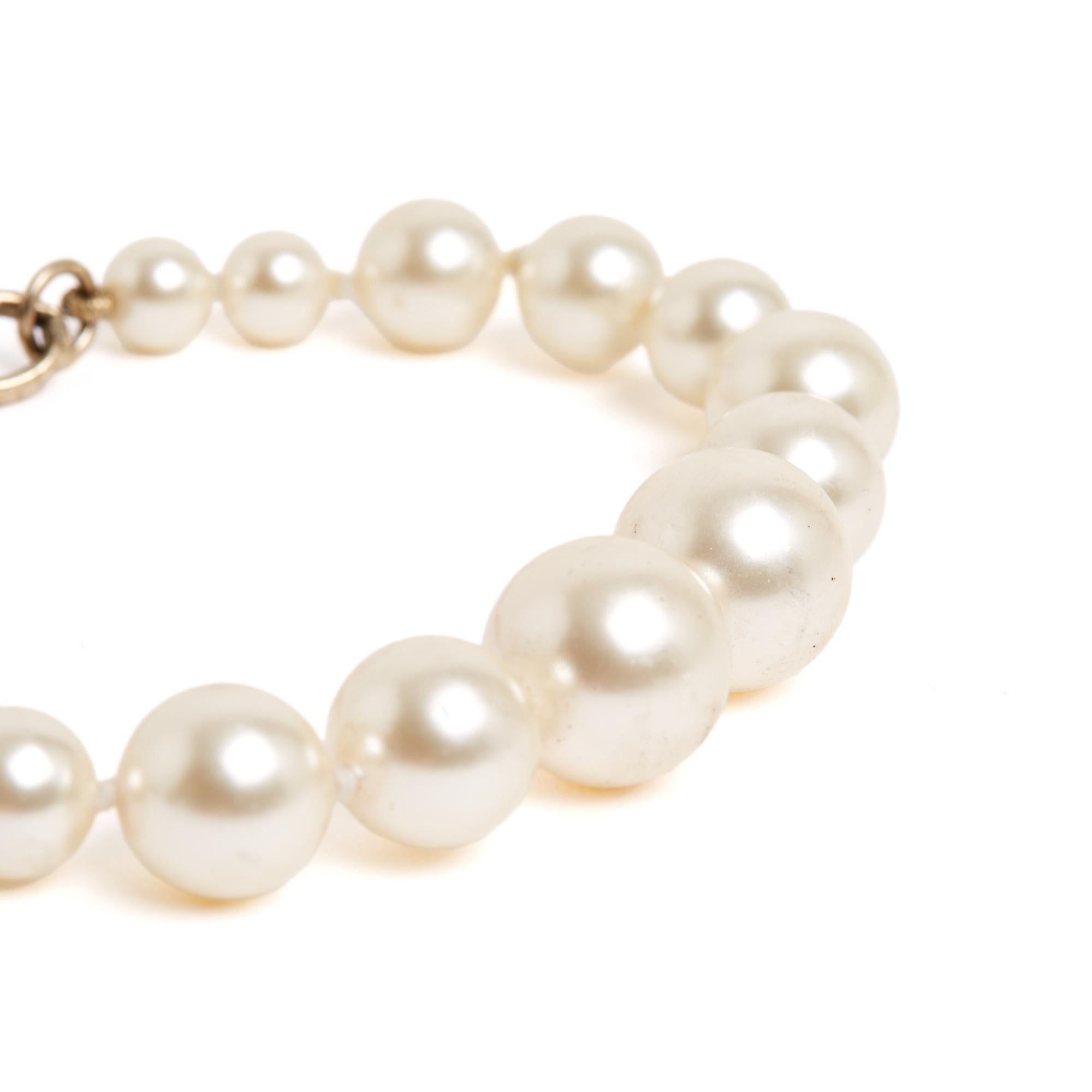 Chanel 2016 bracelet composed of a row of falling fancy pearls, extended by a chain and a pendant or charm with the CC logo motif encrusted with white rhinestones. Total length of the bracelet 20 cm, with the chain but excluding the Chanel logo,