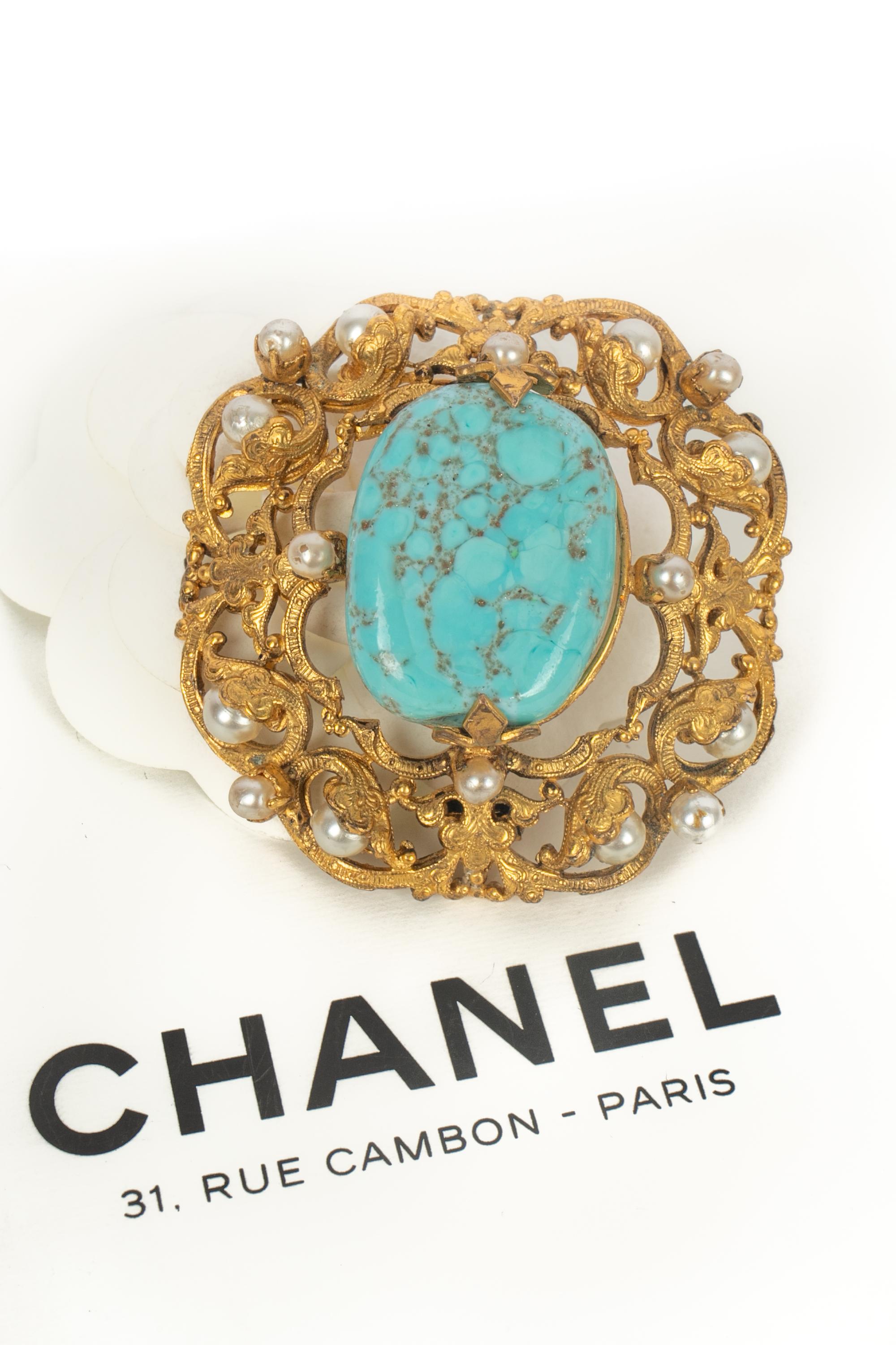 Chanel - Spilla traforata in metallo dorato decorata con perle di costume e sormontata da un'impressionante perla di vetro blu in pasta. Una Collectional dell'era Coco. Realizzato dalla casa Goossens per  Chanel. Gioielli non