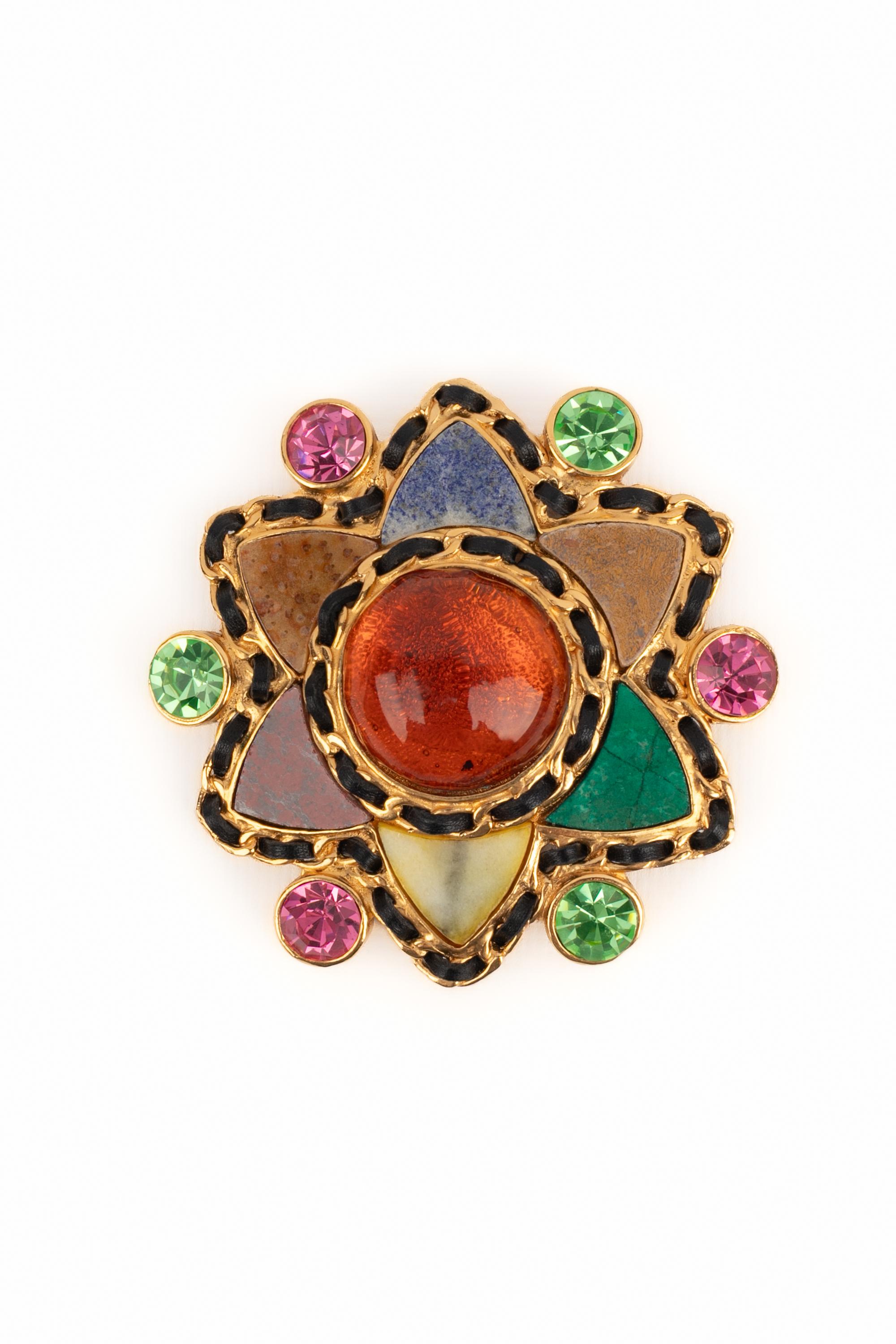 CHANEL - (Made in France) Golden metal brooch with colorful rhinestones, hard stones, and leather. Piece engraved with the S of Sales.

Condition:
Very good condition

Dimensions:
Diameter: 8 cm

SKU:BRB145
