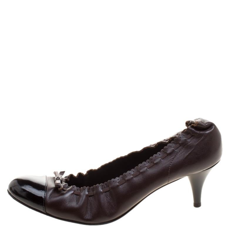 These classic pumps from the house of Chanel feature a textured brown leather body and come with a black leather cap-toe. It features an elasticated opening detailed with tonal stitching and completed with a bow detailing at the vamps. They are set