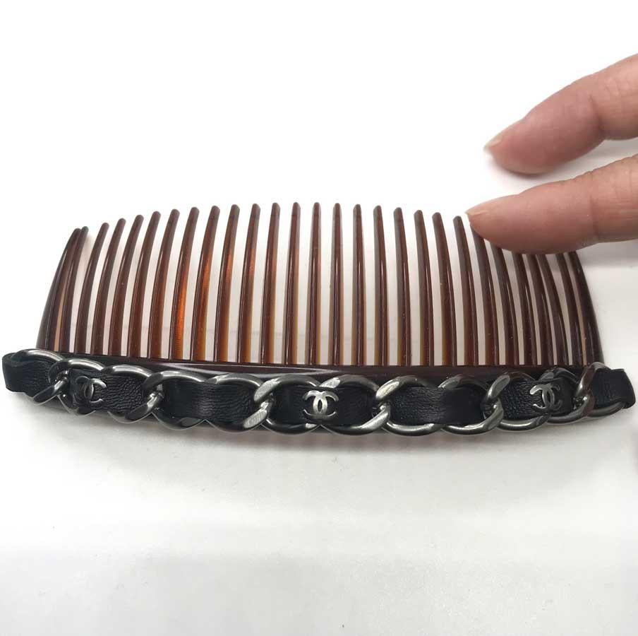 This head jewel comes from Maison CHANEL. The teeth of the comb are brown in color and the jewel is overhung by a metal and leather chain in the CHANEL bag handle style.
The comb is in very good condition. As its pastille indicates, it was made in