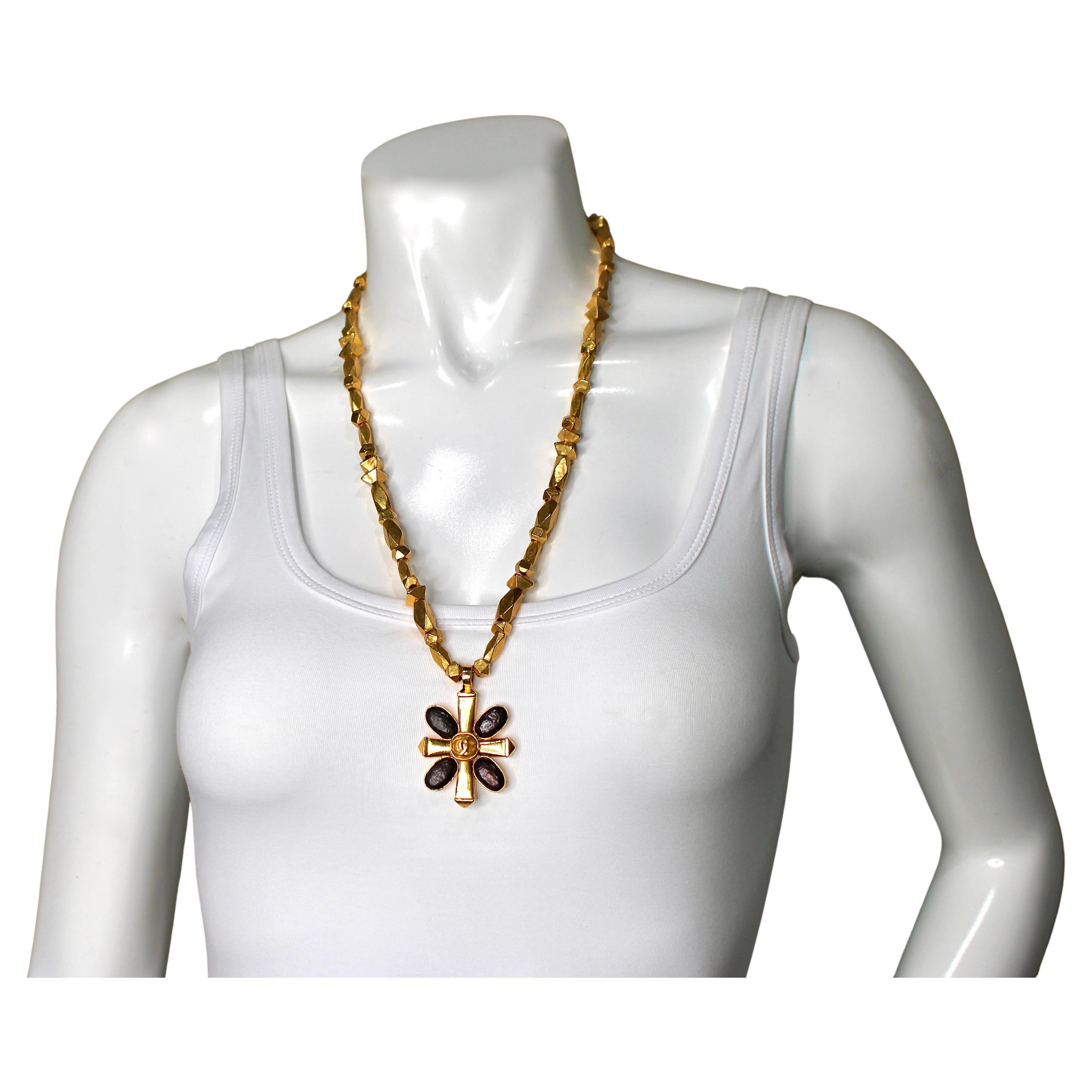The Chanel Brown Gripoix Coco Mark Cross Motif Pendant Necklace from circa 1997 is a stunning example of late 20th-century costume jewelry that combines elegance with designer craftsmanship. The necklace features a luxurious gold-tone beaded chain