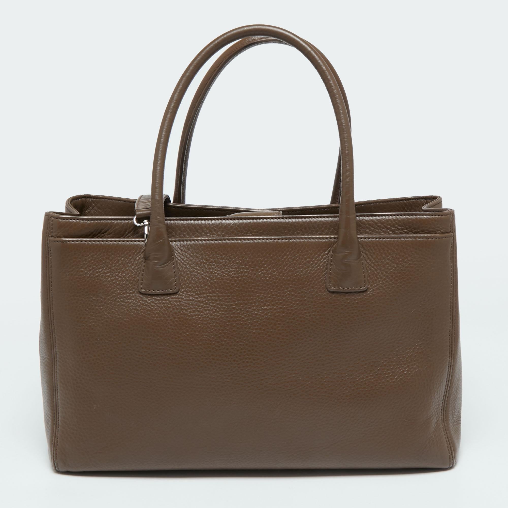 This Cerf tote from Chanel is a perfect blend of function and style. It features a brown leather construction that is enhanced with a metal CC logo on the front and dual top handles. It is equipped with a spacious interior that can easily hold your