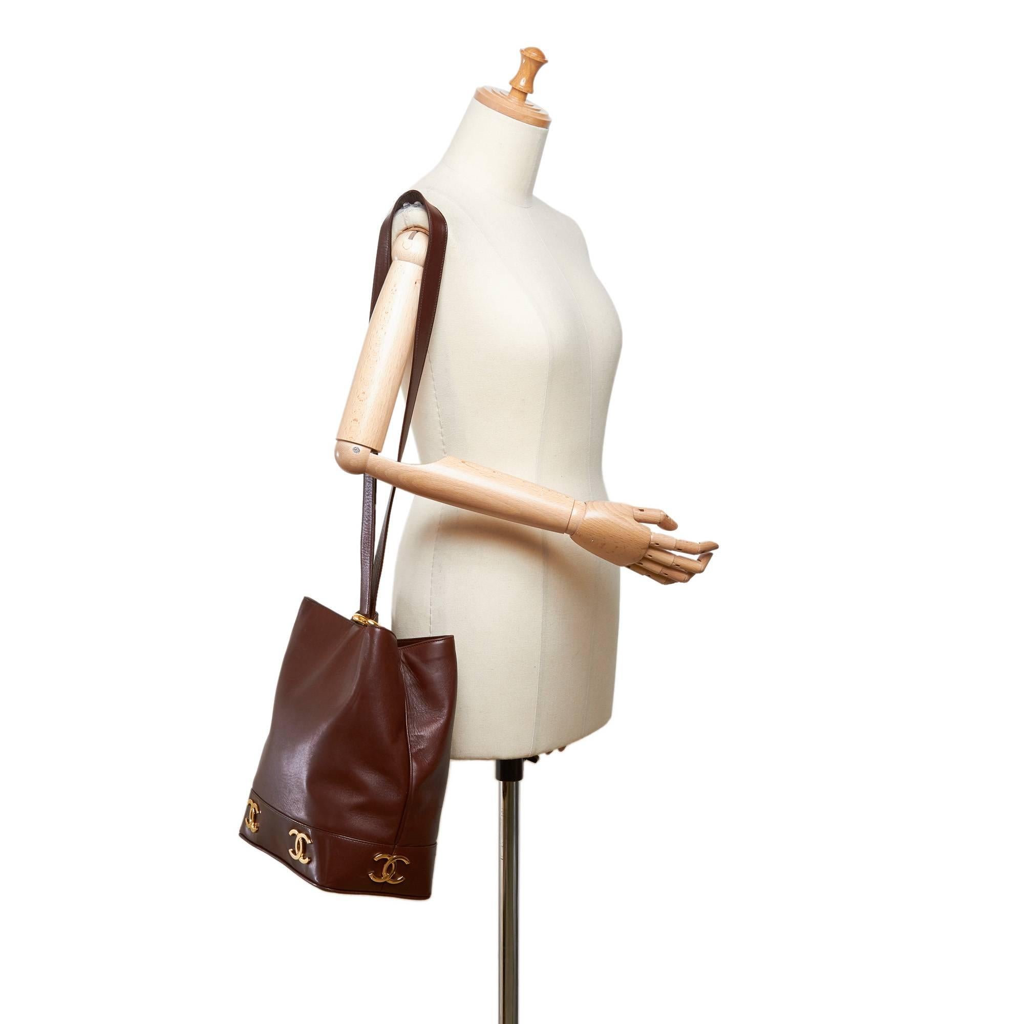 - Vintage 90s Chanel brown leather bucket bag. 

- Featuring single strap with a gold-toned 