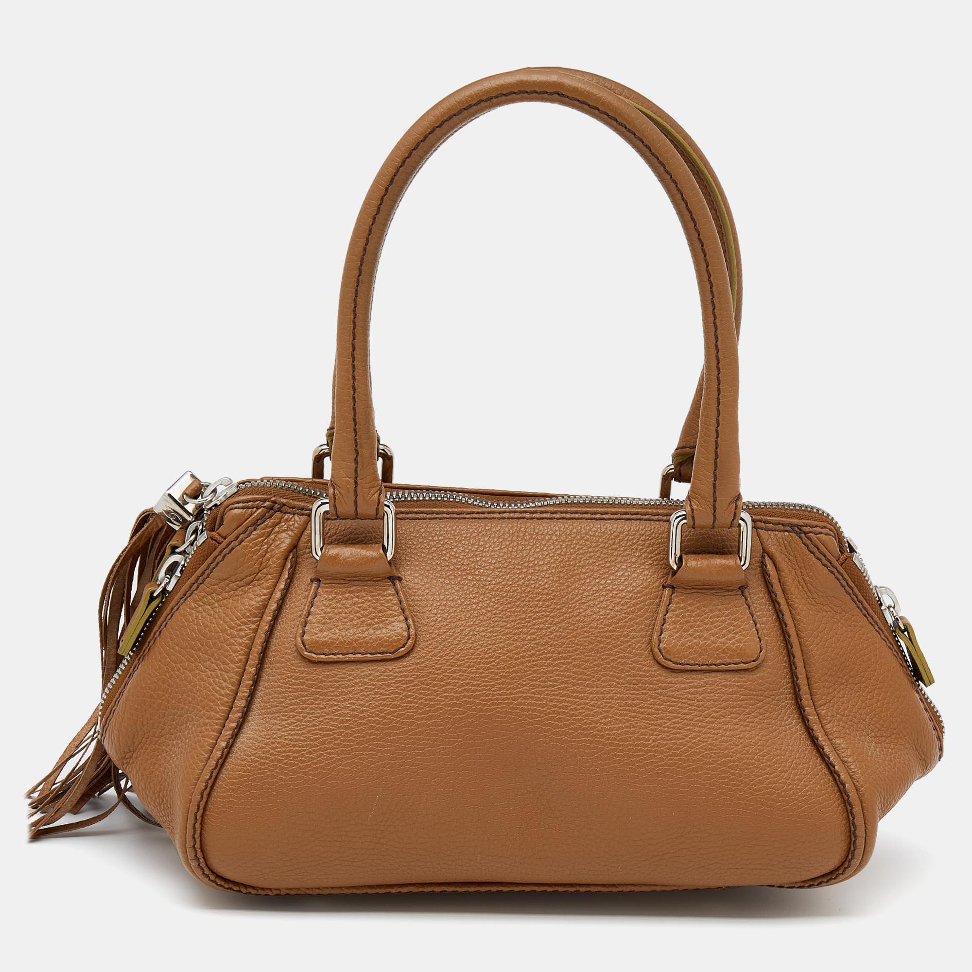 This Chanel LAX Tassel bag is a wear-with-everything accessory. Presented in brown leather, the bag has the brand logo on the front, a tassel attached to the zipper pull, and a fabric interior to house your belongings.