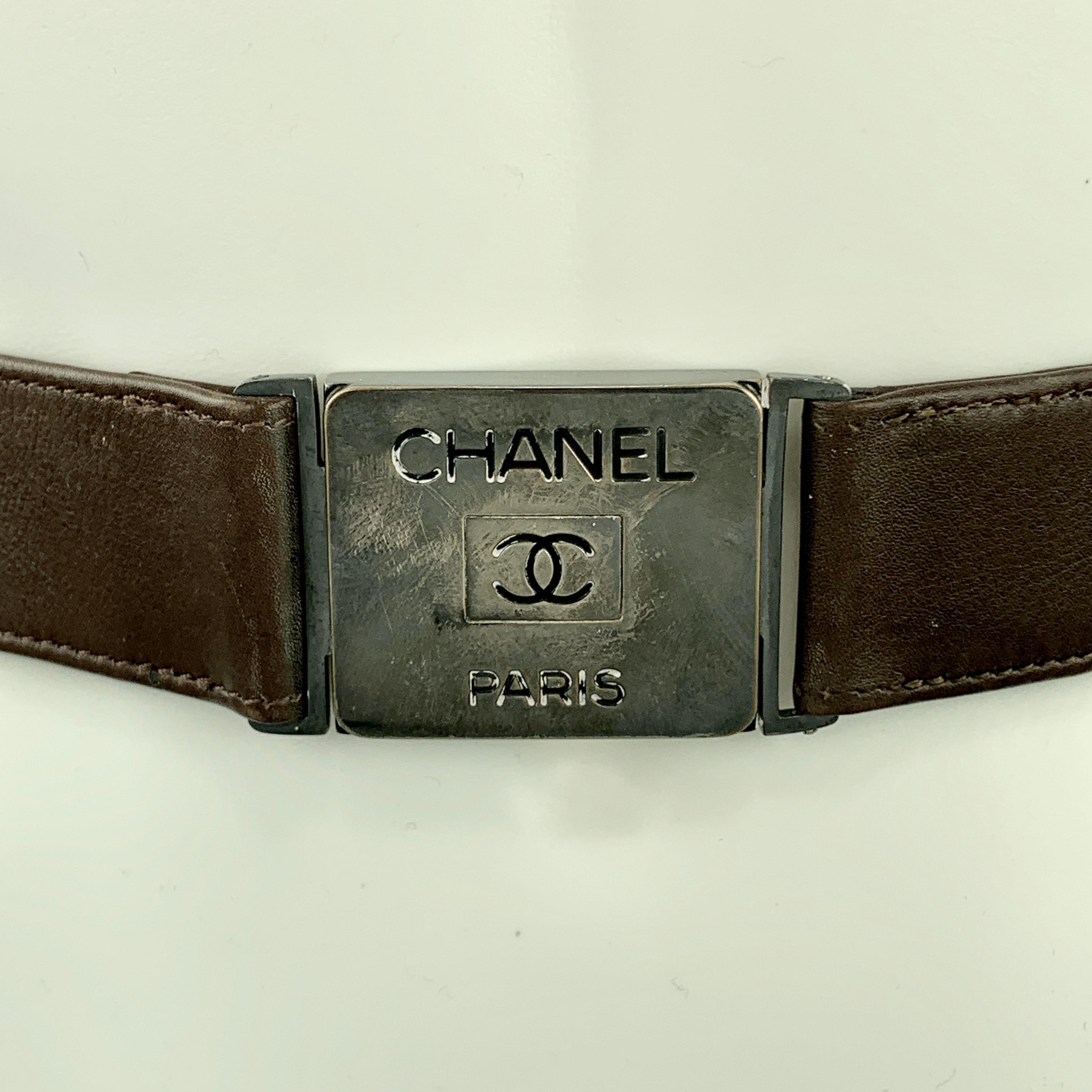 Vintage Spring 1996 Collection CHANEL belt features a brown leather strap with a smoke silver tone logo engraved metal push buckle. Wear on buckle. As-is. Made in France.

Fair Pre-Owned Condition.
Marked: 80/32  96 P

Length: 30 in.
Width: 4
