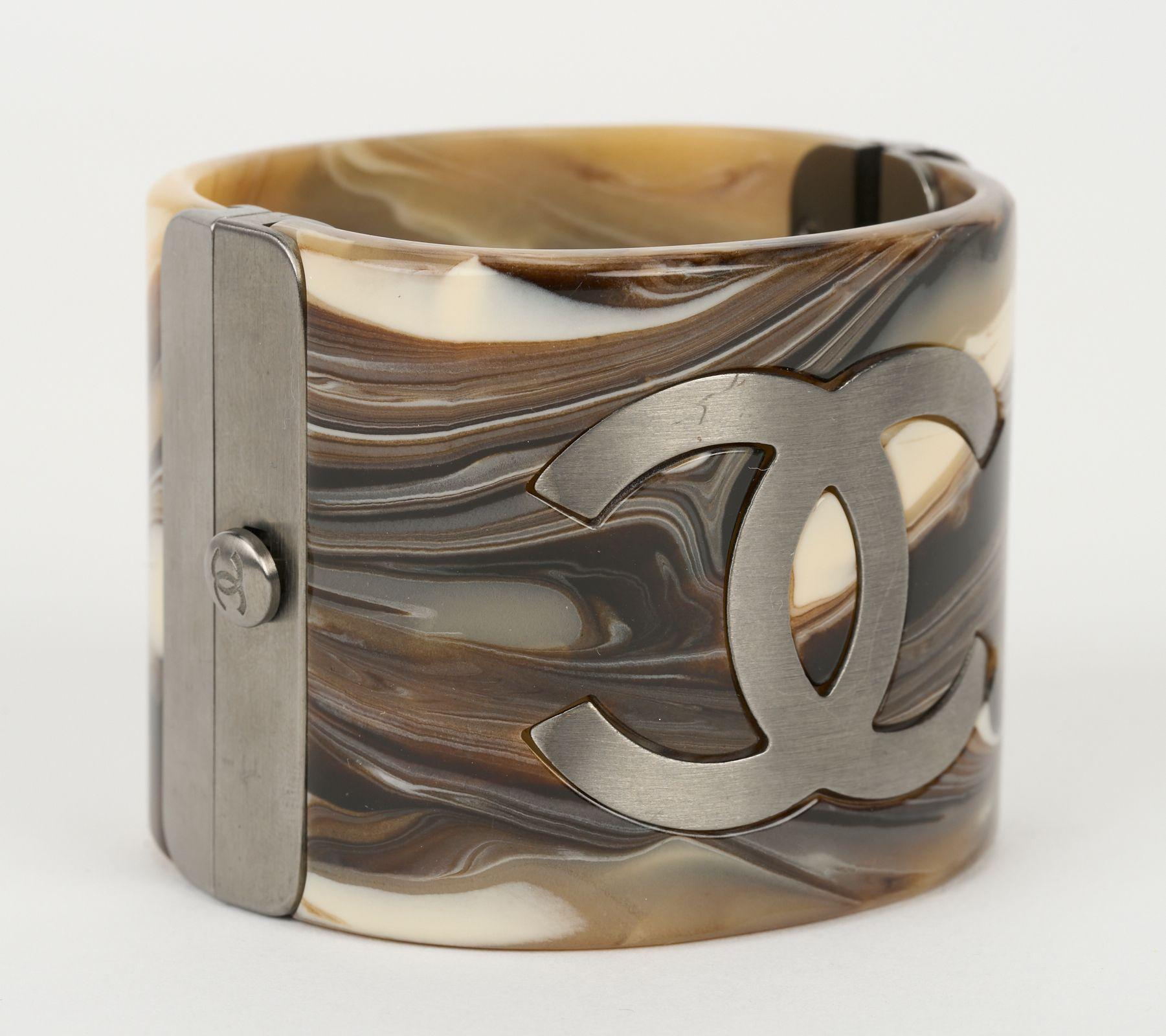 Questo bracciale in resina marrone stampata di Chanel presenta un logo centrale CC inciso e una finitura marrone marmo. Circonferenza interna - 6,5