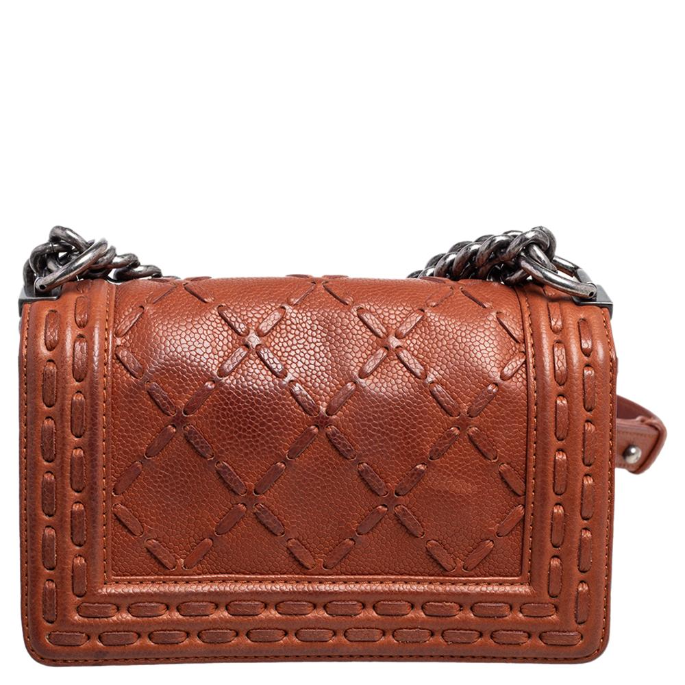 The Boy flap bag is an icon of Chanel's. This here is a version in brown quilted leather. It brings the signature label within the fabric interior and the iconic CC push lock on the flap. The piece has silver-tone hardware and a shoulder chain link